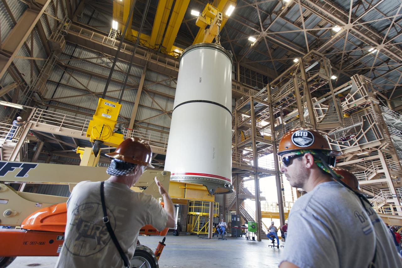 Jacobs technicians, on the Test and Operations Support Contract, practice crane operations with an inert booster rocket segment in the Rotation, Processing and Surge Facility on June 22, 2018, at NASA's Kennedy Space Center in Florida. Dual cranes are being used to move the segment from vertical to horizontal, a maneuver known as a "breakover rotation." As part of routine processing operations for the agency's Space Launch System (SLS) rocket, the RPSF team will receive all of the solid rocket fuel segments for inspection and preparation prior to transporting them to the Vehicle Assembly Building for stacking on the mobile launcher. Many pathfinding operations are being done to prepare for launch of the SLS and Orion spacecraft on Exploration Mission-1 and deep space missions.