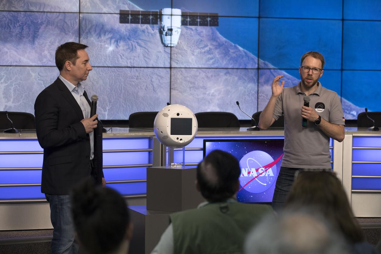Members of the media are shown CIMON, an artificial intelligence system which will assist astronauts on the International Space Station, during a briefing in the Kennedy Space Center’s Press Site auditorium. From left are Bret Greenstein, IBM Global Vice President of Watson and IOT Offerings, and Christian Karrasch, German Space Agency project lead of CIMON. The briefing focused on research planned for launch to the space station. The scientific materials and supplies will be aboard a SpaceX Dragon spacecraft scheduled for liftoff from Cape Canaveral Air Force Station's Space Launch Complex 40. The SpaceX Falcon 9 rocket will launch the company's 15th Commercial Resupply Services mission to the space station.
