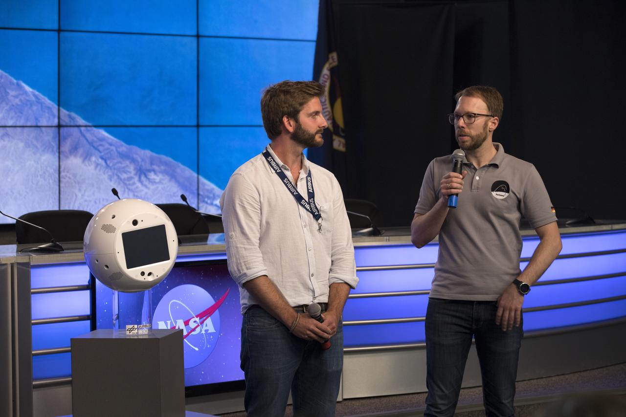 Members of the media are shown CIMON, an artificial intelligence system which will assist astronauts on the International Space Station, during a briefing in the Kennedy Space Center’s Press Site auditorium. From left are AIRBUS CIMON Engineer Philipp Schulien and Christian Karrasch, German Space Agency project lead of CIMON. The briefing focused on research planned for launch to the space station. The scientific materials and supplies will be aboard a SpaceX Dragon spacecraft scheduled for liftoff from Cape Canaveral Air Force Station's Space Launch Complex 40. The SpaceX Falcon 9 rocket will launch the company's 15th Commercial Resupply Services mission to the space station.