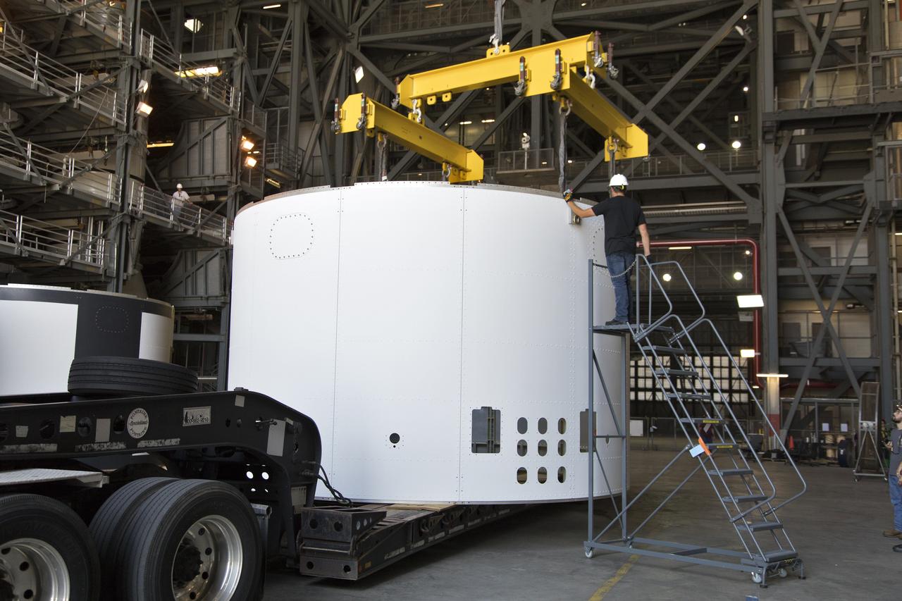 The third and final aeroshell for Orion's Launch Abort System (LAS) arrives by flatbed truck in High Bay 4 of the Vehicle Assembly Building on July 12, 2018, at NASA's Kennedy Space Center in Florida. The aeroshell was shipped from EMF Inc. on nearby Merritt Island. A technician assists with crane attachment so that the aeroshell can be offloaded and placed on slats in the high bay. The aeroshells will be stacked and prepared for a full-stress test of the LAS, called Ascent Abort-2 (AA-2) flight test, scheduled for April 2019. During the test, a booster will launch from Space Launch Complex 46 at Cape Canaveral Air Force Station, carrying a fully functional LAS and a 22,000-pound Orion test vehicle to an altitude of 31,000 feet and traveling at more than 1,000 miles an hour. The test will verify the LAS can steer the crew module and astronauts aboard to safety in the event of an issue with the Space Launch System (SLS) rocket when the spacecraft is under the highest aerodynamic loads it will experience during a rapid climb into space. Orion is being prepared for its first integrated uncrewed flight atop the SLS on Exploration Mission-1.