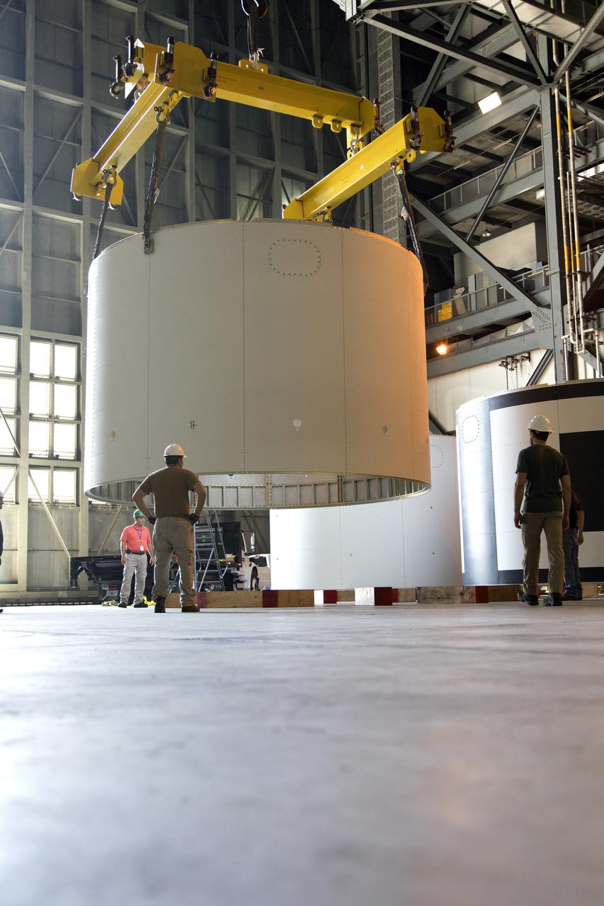 Technicians assist as a crane lowers the third and final aeroshell for Orion's Launch Abort System (LAS) onto slats in High Bay 4 of the Vehicle Assembly Building on July 12, 2018, at NASA's Kennedy Space Center in Florida. The aeroshell was shipped from EMF Inc. on nearby Merritt Island. All three aeroshells will be stacked and prepared for a full-stress test of the LAS, called Ascent Abort-2 (AA-2) flight test, scheduled for April 2019. During the test, a booster will launch from Space Launch Complex 46 at Cape Canaveral Air Force Station, carrying a fully functional LAS and a 22,000-pound Orion test vehicle to an altitude of 31,000 feet and traveling at more than 1,000 miles an hour. The test will verify the LAS can steer the crew module and astronauts aboard to safety in the event of an issue with the Space Launch System (SLS) rocket when the spacecraft is under the highest aerodynamic loads it will experience during a rapid climb into space. Orion is being prepared for its first integrated uncrewed flight atop the SLS on Exploration Mission-1.