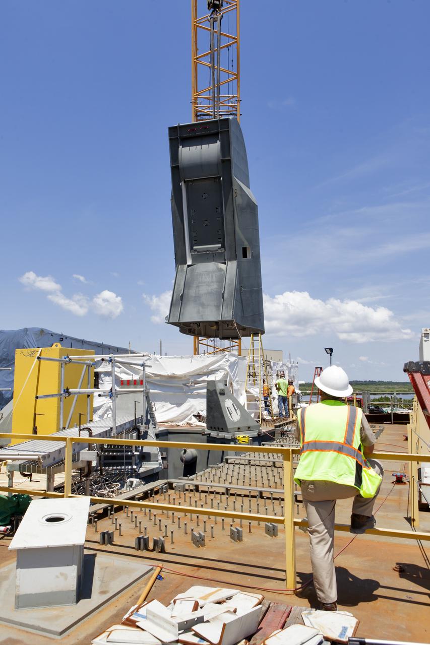 A crane is used to lower the first of two Tail Service Mast Umbilicals for installation on the 0-level deck of the mobile launcher on July 12, at NASA's Kennedy Space Center in Florida. The 35-foot-tall umbilical will connect to NASA's Space Launch System rocket core stage aft section and provide liquid oxygen and electrical cable connections to the core stage engine section to support propellant handling during prelaunch operations. The installation brings Exploration Ground Systems one step closer to supporting prelaunch operations for the agency's SLS rocket and Orion spacecraft on Exploration Mission-1 and deep space destinations.