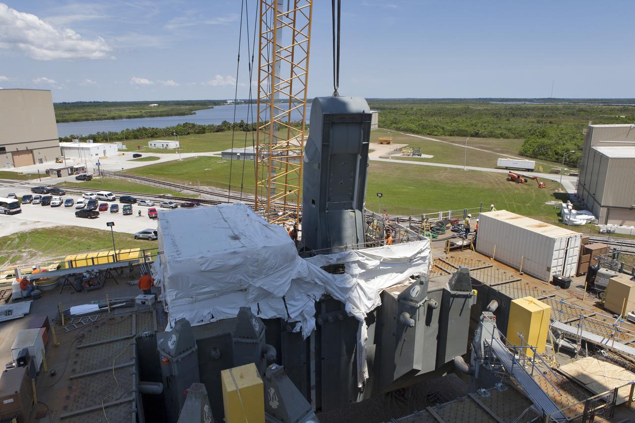 A crane is used to lower the first of two Tail Service Mast Umbilicals for installation on the 0-level deck of the mobile launcher on July 12, at NASA's Kennedy Space Center in Florida. The 35-foot-tall umbilical will connect to NASA's Space Launch System rocket core stage aft section and provide liquid oxygen and electrical cable connections to the core stage engine section to support propellant handling during prelaunch operations. The installation brings Exploration Ground Systems one step closer to supporting prelaunch operations for the agency's SLS rocket and Orion spacecraft on Exploration Mission-1 and deep space destinations.
