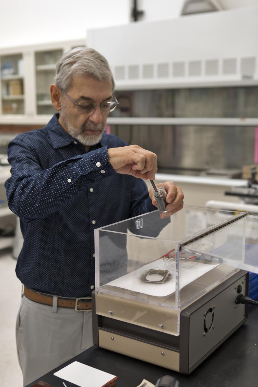 Dr. Carlos Calle, lead scientist in the Electrostatics and Surface Physics Laboratory at NASA's Kennedy Space Center in Florida, prepares an Electrostatic Dust Shield for testing on Thursday, July 19, 2018. Scientists are developing the Electrostatic Dust Shield to help mitigate the problem of dust on equipment, astronauts' space suits and helmet visors of astronauts exploring the Moon or Mars. The device is slated for analysis aboard International Space Station in the spring of 2019 to verify the effects of the space environment.