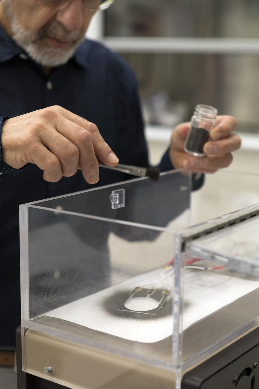 Dr. Carlos Calle, lead scientist in the Electrostatics and Surface Physics Laboratory at NASA's Kennedy Space Center in Florida, prepares an Electrostatic Dust Shield for testing on Thursday, July 19, 2018. Scientists are developing the Electrostatic Dust Shield to help mitigate the problem of dust on equipment, astronauts' space suits and helmet visors of astronauts exploring the Moon or Mars. The device is slated for analysis aboard International Space Station in the spring of 2019 to verify the effects of the space environment.