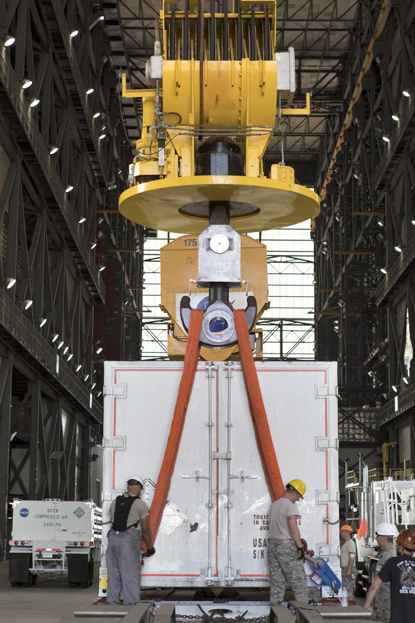 In the transfer aisle inside the Vehicle Assembly Building (VAB) at NASA's Kennedy Space Center in Florida, Jacob’s technicians on the Test Operations Support Contract attach a crane to a shipping container with the ground test motor for Orion's Launch Abort System (LAS) inside on July 20, 2018. The container will be lifted and transferred to another transporter and moved to the Rotation, Processing and Surge Facility where it will be inspected and prepared for transport to Space Launch Complex 46 (SLC-46) at Cape Canaveral Air Force Station for mechanical fit testing. This inert motor will not be used for flight, but will be used to certify flight hardware assembly in preparation for a full-stress test of the LAS, called Ascent Abort-2 (AA-2) flight test, scheduled for April 2019. During the test, the booster will launch from SLC 46, carrying a fully functional LAS and a 22,000-pound Orion test vehicle to an altitude of 31,000 feet and traveling at more than 1,000 miles an hour. The test will verify the LAS can steer the crew module and astronauts aboard to safety in the event of an issue with the Space Launch System (SLS) rocket when the spacecraft is under the highest aerodynamic loads it will experience during a rapid climb into space. NASA's Orion and Exploration Ground Systems programs and their contractors from Jacob's and Northrup Grumman in conjunction with the Air Force Space and Missile Center's Launch Operations branch SMC/LEXO, are performing the pathfinding exercises and flight operations for AA-2.