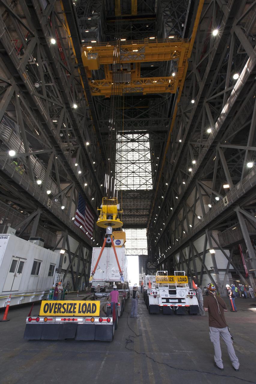 In the transfer aisle inside the Vehicle Assembly Building (VAB) at NASA's Kennedy Space Center in Florida, a crane is used to lift up a shipping container with the ground test motor for Orion's Launch Abort System (LAS) inside on July 20, 2018. The container will be lifted and transferred to another transporter and moved to the Rotation, Processing and Surge Facility where it will be inspected and prepared for transport to Space Launch Complex 46 (SLC-46) at Cape Canaveral Air Force Station for mechanical fit testing. This inert motor will not be used for flight, but will be used to certify flight hardware assembly in preparation for a full-stress test of the LAS, called Ascent Abort-2 (AA-2) flight test, scheduled for April 2019. During the test, the booster will launch from SLC 46, carrying a fully functional LAS and a 22,000-pound Orion test vehicle to an altitude of 31,000 feet and traveling at more than 1,000 miles an hour. The test will verify the LAS can steer the crew module and astronauts aboard to safety in the event of an issue with the Space Launch System (SLS) rocket when the spacecraft is under the highest aerodynamic loads it will experience during a rapid climb into space. NASA's Orion and Exploration Ground Systems programs and their contractors from Jacob's and Northrup Grumman in conjunction with the Air Force Space and Missile Center's Launch Operations branch SMC/LEXO, are performing the pathfinding exercises and flight operations for AA-2.