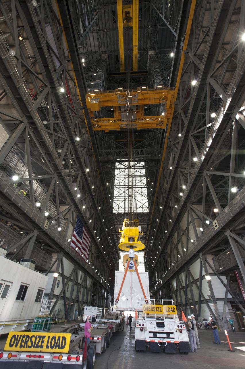 In the transfer aisle inside the Vehicle Assembly Building (VAB) at NASA's Kennedy Space Center in Florida, a crane is used to lift up the shipping container with the ground test motor for Orion's Launch Abort System (LAS) inside on July 20, 2018. The container will be lowered onto another transporter and moved to the Rotation, Processing and Surge Facility where it will be inspected and prepared for transport to Space Launch Complex 46 (SLC-46) at Cape Canaveral Air Force Station for mechanical fit testing. This inert motor will not be used for flight, but will be used to certify flight hardware assembly in preparation for a full-stress test of the LAS, called Ascent Abort-2 (AA-2) flight test, scheduled for April 2019. During the test, the booster will launch from SLC 46, carrying a fully functional LAS and a 22,000-pound Orion test vehicle to an altitude of 31,000 feet and traveling at more than 1,000 miles an hour. The test will verify the LAS can steer the crew module and astronauts aboard to safety in the event of an issue with the Space Launch System (SLS) rocket when the spacecraft is under the highest aerodynamic loads it will experience during a rapid climb into space. NASA's Orion and Exploration Ground Systems programs and their contractors from Jacob's and Northrup Grumman in conjunction with the Air Force Space and Missile Center's Launch Operations branch SMC/LEXO, are performing the pathfinding exercises and flight operations for AA-2.