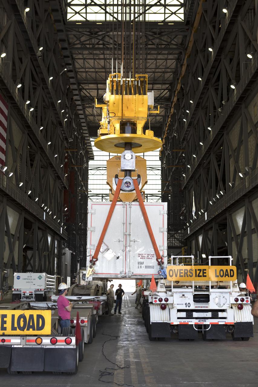 In the transfer aisle inside the Vehicle Assembly Building (VAB) at NASA's Kennedy Space Center in Florida, a crane is used to lift up the shipping container with the ground test motor for Orion's Launch Abort System (LAS) inside on July 20, 2018. The container will be lowered onto another transporter and moved to the Rotation, Processing and Surge Facility where it will be inspected and prepared for transport to Space Launch Complex 46 (SLC-46) at Cape Canaveral Air Force Station for mechanical fit testing. This inert motor will not be used for flight, but will be used to certify flight hardware assembly in preparation for a full-stress test of the LAS, called Ascent Abort-2 (AA-2) flight test, scheduled for April 2019. During the test, the booster will launch from SLC 46, carrying a fully functional LAS and a 22,000-pound Orion test vehicle to an altitude of 31,000 feet and traveling at more than 1,000 miles an hour. The test will verify the LAS can steer the crew module and astronauts aboard to safety in the event of an issue with the Space Launch System (SLS) rocket when the spacecraft is under the highest aerodynamic loads it will experience during a rapid climb into space. NASA's Orion and Exploration Ground Systems programs and their contractors from Jacob's and Northrup Grumman in conjunction with the Air Force Space and Missile Center's Launch Operations branch SMC/LEXO, are performing the pathfinding exercises and flight operations for AA-2.
