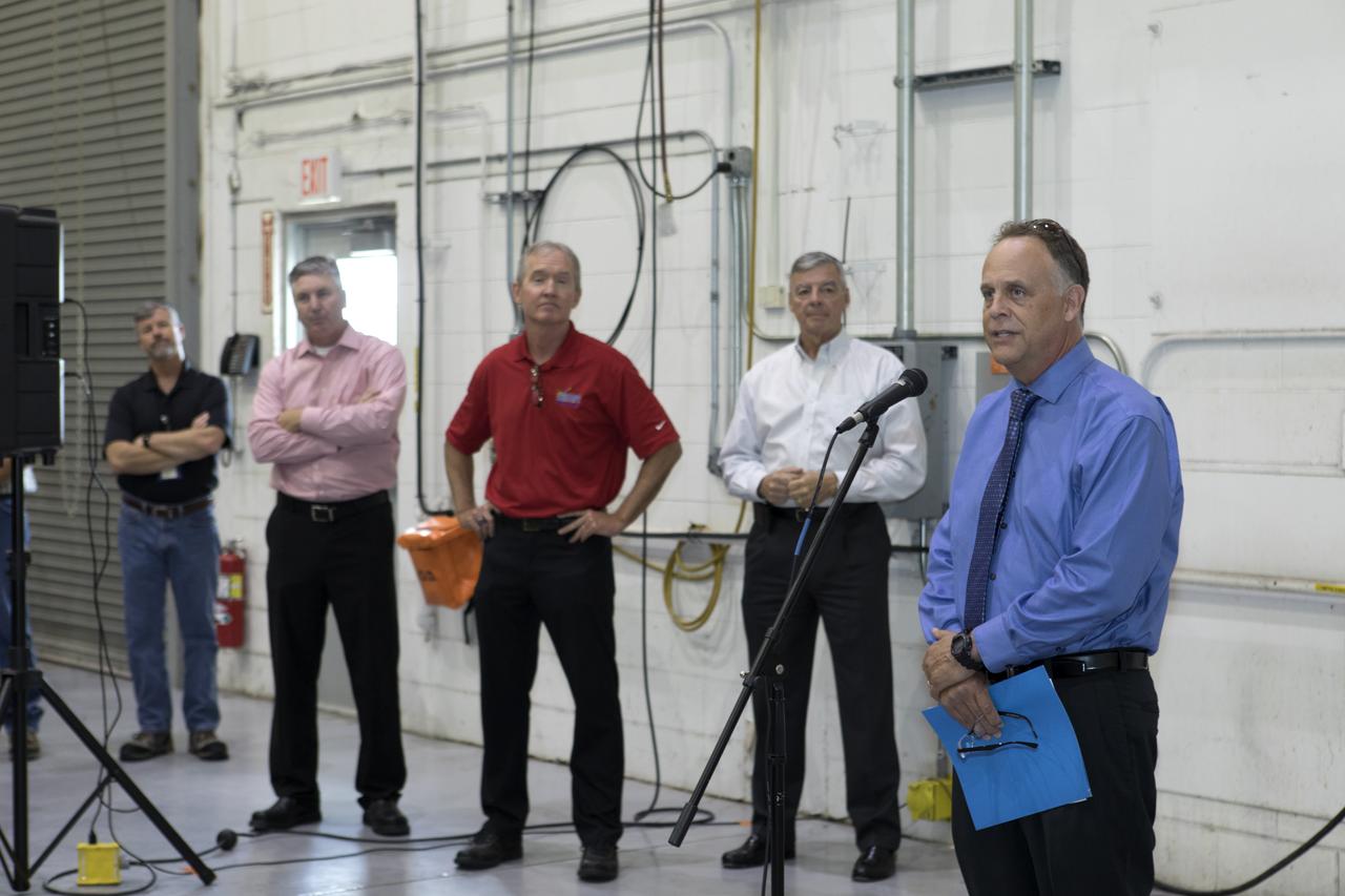 The team that tested the umbilical lines and accessories that will connect from the mobile launcher to NASA's Space Launch System rocket and Orion spacecraft for Exploration Mission-1 hold a banner signing event July 24, 2018, to mark completion of testing at the Launch Equipment Test Facility (LETF) at NASA's Kennedy Space Center in Florida. Speaking at the event is Shawn Quinn, far right, director of Engineering. Next to him, from left, are Scott Colloredo, deputy director of Engineering; Russ Deloach, director of Safety and Mission Assurance; and Andy Allen, program manager for Jacobs TOSC. A total of 21 umbilicals and launch accessories were tested on various simulators at the LETF before they were transferred to the mobile launcher for installation.
