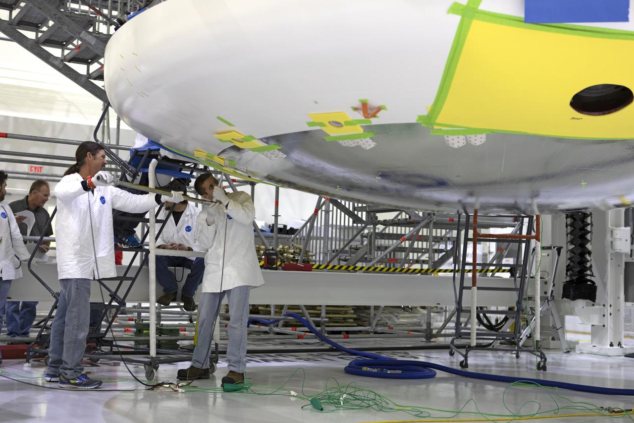 Lockheed Martin engineers and technicians are installing the heat shield to the Orion crew module July 25, 2018, inside the Neil Armstrong Operations and Checkout Building high bay at NASA's Kennedy Space Center in Florida. Orion is being prepared for Exploration Mission-1 (EM-1). The Orion spacecraft will launch atop NASA's Space Launch System rocket on its first uncrewed integrated flight. The heat shield will need to withstand temperatures of up to 5,000 degrees Fahrenheit during Orion's descent and re-entry through the Earth's atmosphere before it splashes down in the Pacific Ocean.