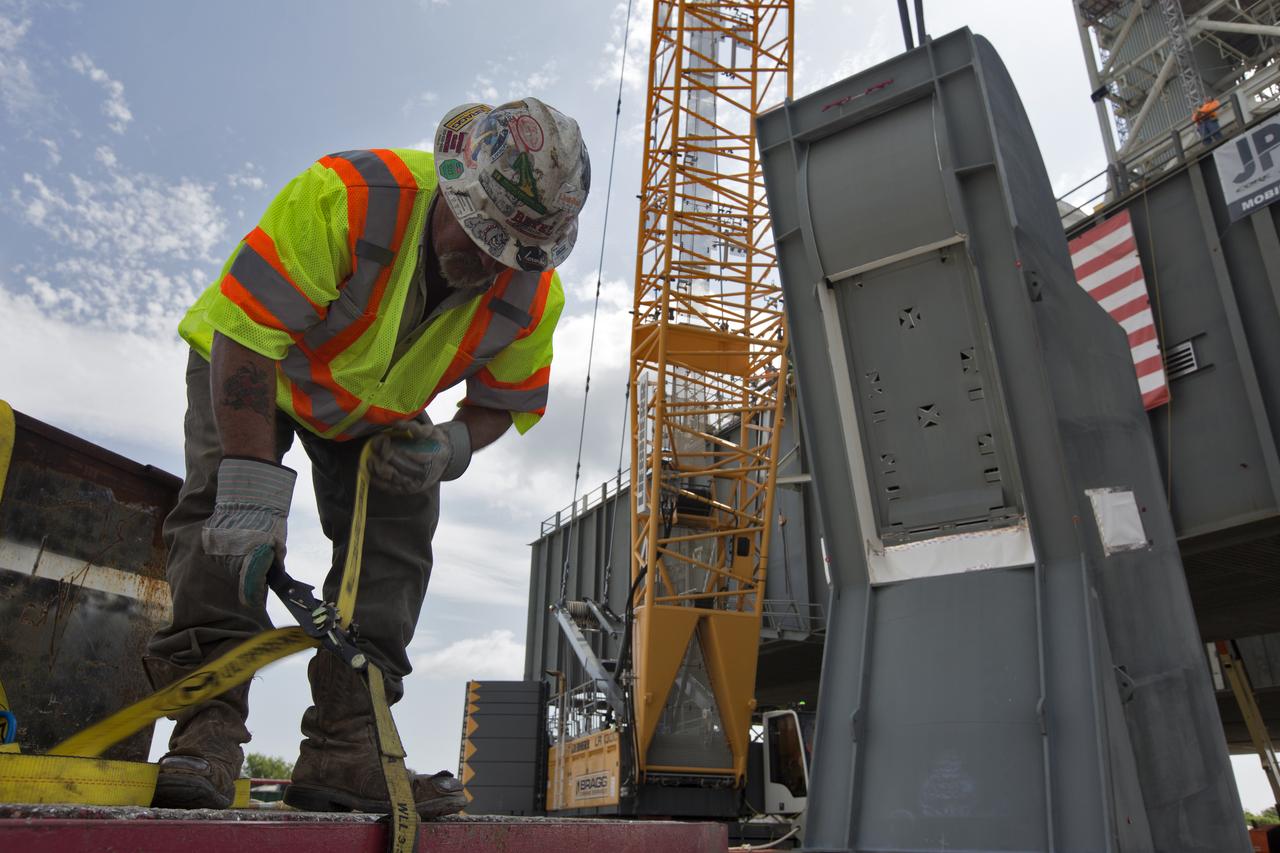 A JP Donovan construction worker makes preparations for lifting of the second of two Tail Service Mast Umbilicals for installation on the 0-level deck of the mobile launcher on July 27, at NASA's Kennedy Space Center in Florida. The 35-foot-tall umbilical will connect to NASA's Space Launch System (SLS) rocket core stage aft section and provide hydrogen and electrical cable connections to the core stage engine section to support propellant handling during prelaunch operations. The installation brings Exploration Ground Systems one step closer to supporting prelaunch operations for the agency's SLS rocket and Orion spacecraft on Exploration Mission-1 and deep space destinations.