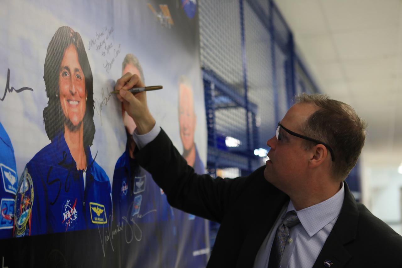 During a tour of Boeing's Commercial Crew and Cargo Processing Facility (C3PF), NASA Administrator Jim Bridenstine signs a banner with photos of astronauts chosen for the first Commercial Crew Program flights. The C3PF is the production and processing home of Boeing’s CST-100 Starliner spacecraft. Bridenstine made his first official visit to NASA's Kennedy Space Center on Aug. 6 and 7, 2018.