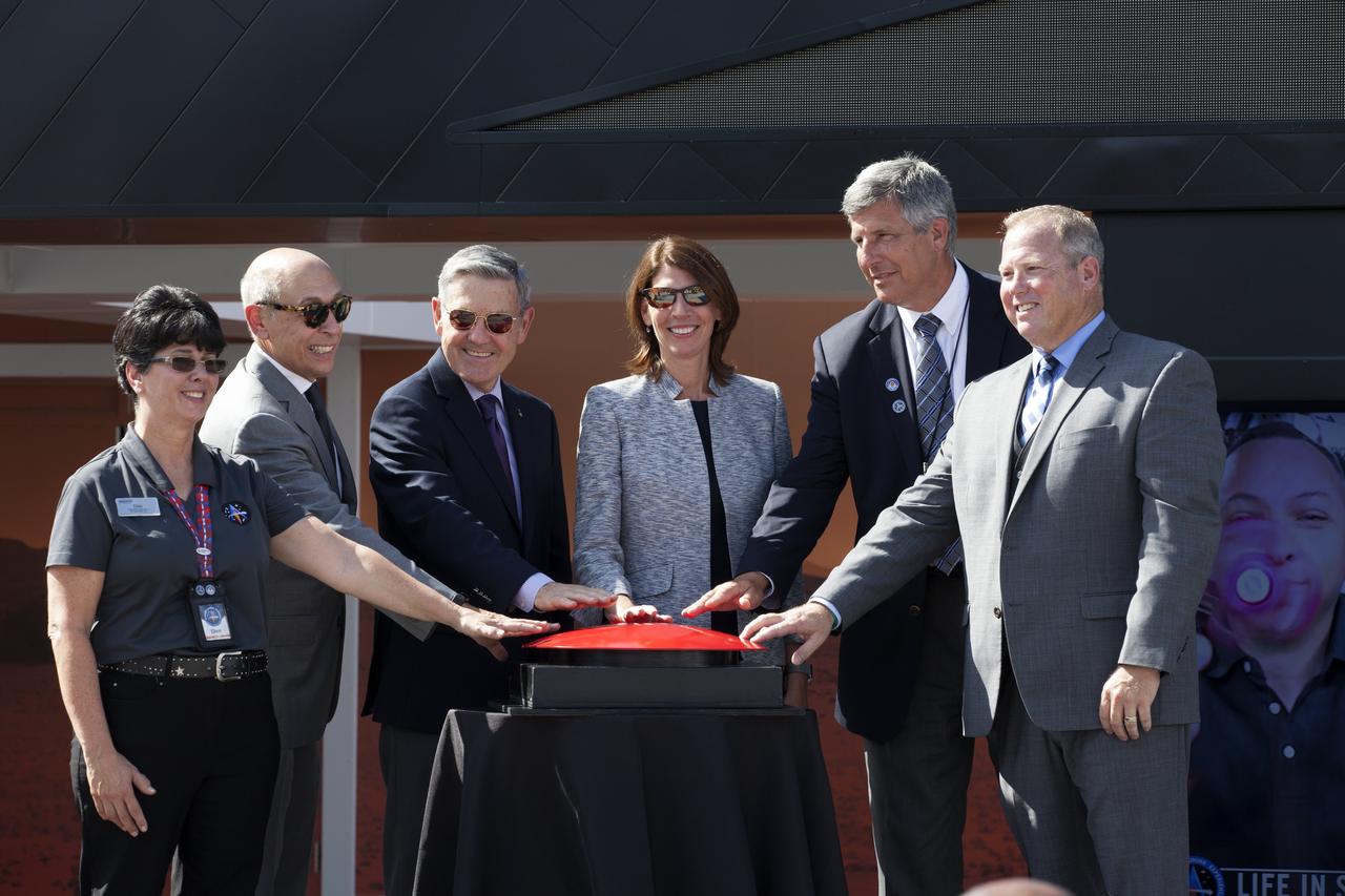 Officials at the Kennedy Space Center Visitor Complex prepare to push a ceremonial button to "launch" the facility's new Astronaut Training Experience (ATX). Participating, from the left, are: Dee Maynard, private education program manager for the Kennedy visitor complex, Rick Abramson, chief customer officer for Delaware North, Kennedy Director Bob Cabana, Lisa Callahan vice president and general manager of Commercial Civil Space at Lockheed Martin Space, Jim Houser, executive vice president and chief operating officer for Delaware North, and Therrin Protze, chief operating officer of the Kennedy visitor complex. The ATX uses three-dimensional computer display simulation technology to "transport" participants to Mars, training them to live and work in the environment of the Red Planet. The educational experience also teaches what it’s like to travel there. The facility uses NASA science to address engineering challenges in space travel. Lockheed Martin is the title sponsor for the Astronaut Training Experience.