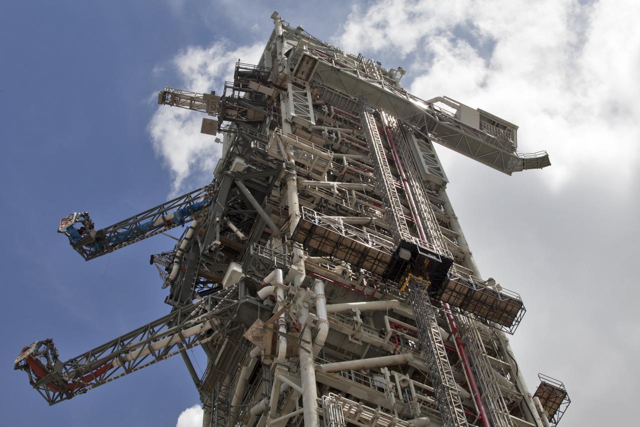 A swing test of the Orion crew access arm, top right, begins on the mobile launcher at NASA's Kennedy Space Center in Florida, on Aug. 21, 2018. The crew access arm is located at about the 274-foot level on the mobile launcher tower. It will rotate from its retracted position and interface with the Orion crew hatch location to provide entry to the Orion crew module. Exploration Ground Systems extended all of the launch umbilicals on the ML tower to test their functionality before the mobile launcher, atop crawler-transporter 2, is moved to Launch Pad 39B and the Vehicle Assembly Building.