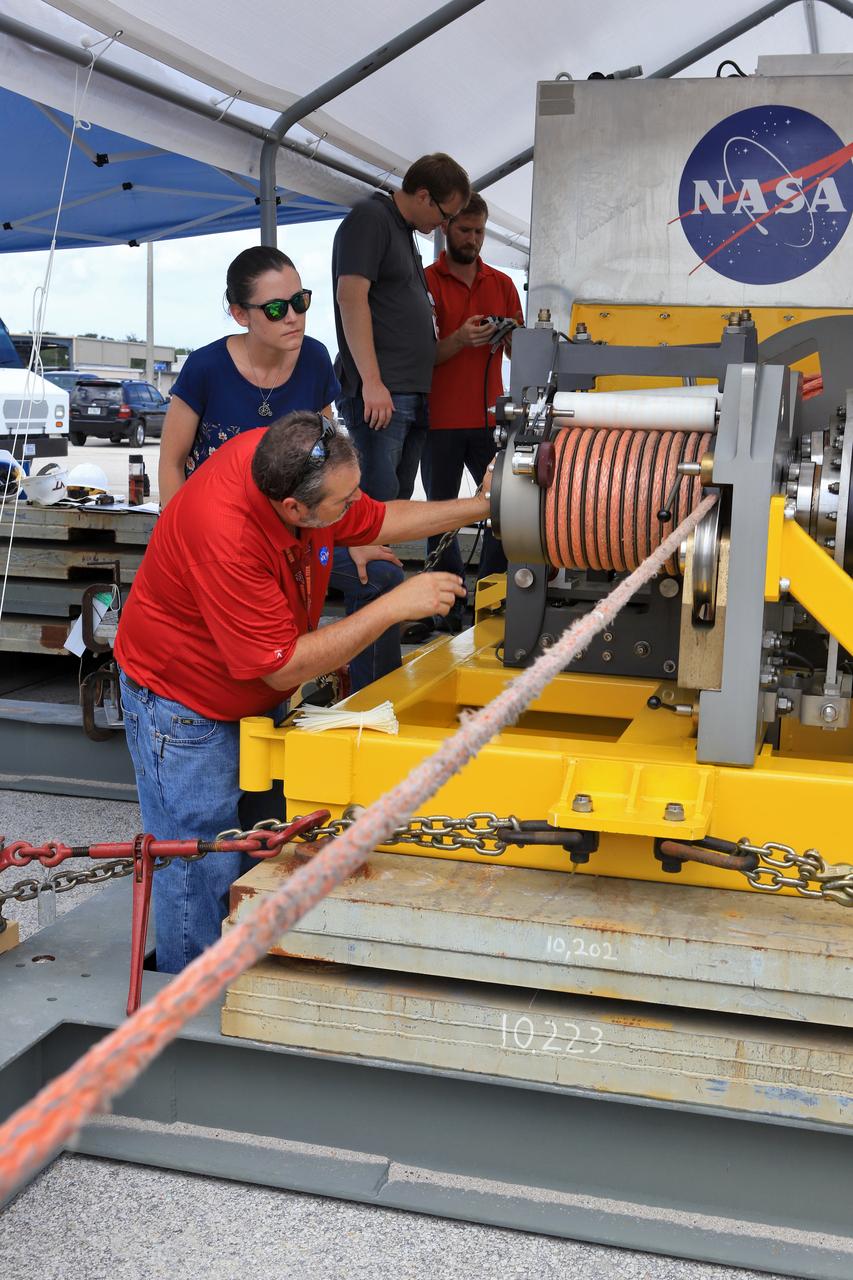 Orion Landing and Recovery team members with Jacobs, practice using a winch to prepare for Underway Recovery Test 7 (URT-7) on Sept. 5, 2018, in the heavy equipment yard at NASA's Kennedy Space Center in Florida. From left, are handling and access engineers Pete Ruett, Amy Hein, Peter Thorn and Eric Hernandez. During URT-7, the recovery team, including Exploration Ground Systems and the U.S. Navy, will practice recovering a test version of the Orion crew module in the Pacific Ocean, off the coast of California, and guiding it into the well deck of a ship. Over several days, the team will demonstrate and evaluate new recovery processes, procedures, hardware and personnel in open waters. Orion is the exploration spacecraft designed to carry astronauts to deep space destinations, including the Moon and on to Mars. Orion will have emergency abort capability, sustain the crew during space travel and provide safe re-entry from deep space return velocities.