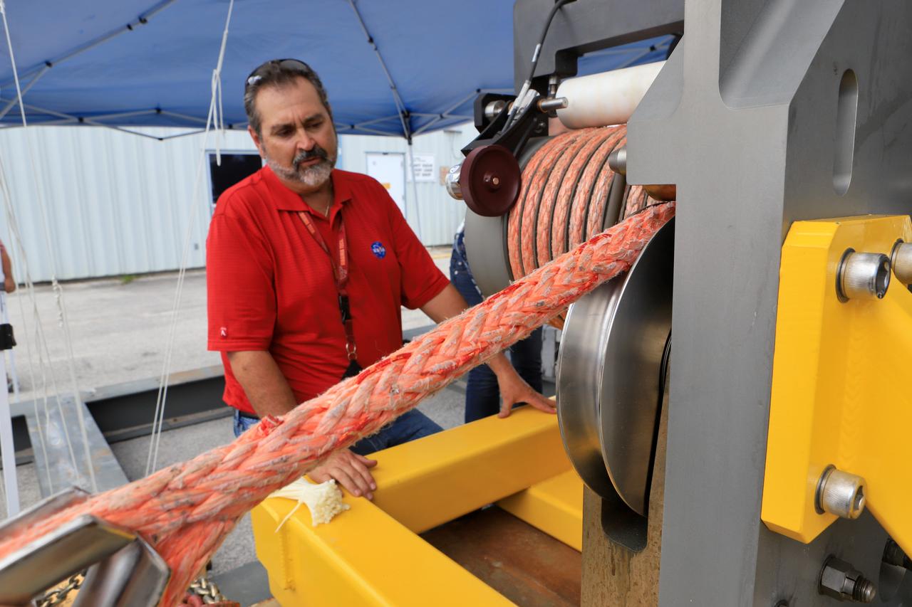 Orion Landing and Recovery team member Pete Ruett, with Jacobs, practices using a winch to prepare for Underway Recovery Test 7 (URT-7) on Sept. 5, 2018, in the heavy equipment yard at NASA's Kennedy Space Center in Florida. Ruett is a handling and access engineer. During URT-7, the recovery team, including Exploration Ground Systems and the U.S. Navy, will practice recovering a test version of the Orion crew module in the Pacific Ocean, off the coast of California, and guiding it into the well deck of a ship. Over several days, the team will demonstrate and evaluate new recovery processes, procedures, hardware and personnel in open waters. Orion is the exploration spacecraft designed to carry astronauts to deep space destinations, including the Moon and on to Mars. Orion will have emergency abort capability, sustain the crew during space travel and provide safe re-entry from deep space return velocities.