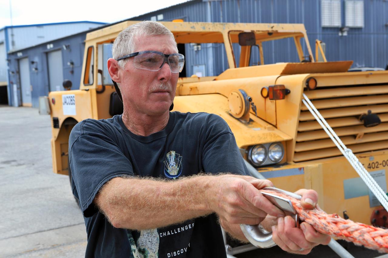 Orion Landing and Recovery team member John Stirling, with Jacobs, practices using a winch to prepare for Underway Recovery Test 7 ( URT-7) on Sept. 5, 2018, in the heavy equipment yard at NASA's Kennedy Space Center in Florida. During URT-7, the recovery team, including Exploration Ground Systems and the U.S. Navy, will practice recovering a test version of the Orion crew module in the Pacific Ocean, off the coast of California, and guiding it into the well deck of a ship. Over several days, the team will demonstrate and evaluate new recovery processes, procedures, hardware and personnel in open waters. Orion is the exploration spacecraft designed to carry astronauts to deep space destinations, including the Moon and on to Mars. Orion will have emergency abort capability, sustain the crew during space travel and provide safe re-entry from deep space return velocities.