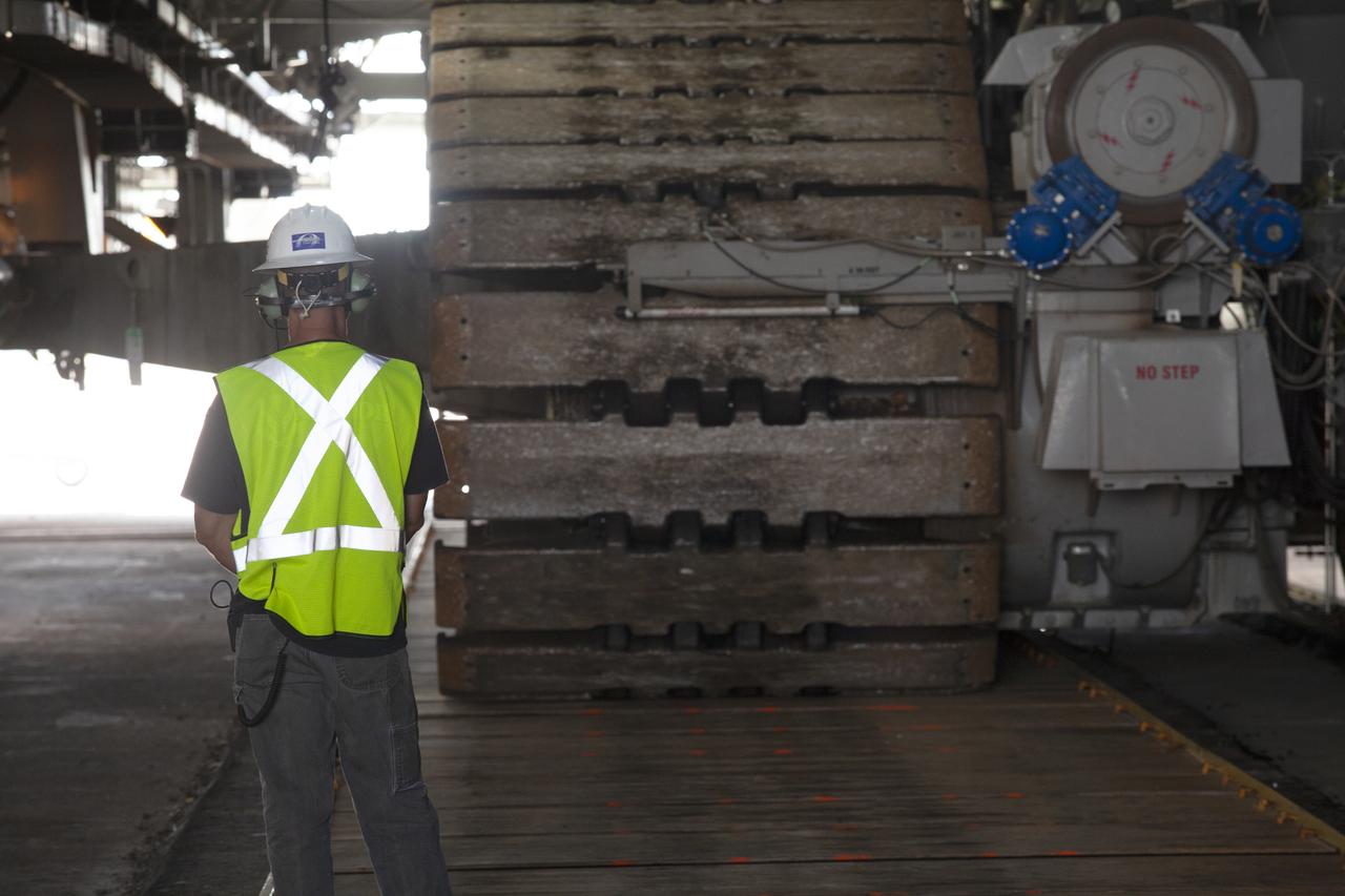 The giant cleats of crawler-transporter 2 are in view as a technician monitors the progress of the move of NASA's mobile launcher, atop the crawler, into High Bay 3 at the Vehicle Assembly Building (VAB) on Sept. 8, 2018, at NASA's Kennedy Space Center in Florida. The mobile launcher departed Launch Pad 39B after several days of testing with the pad. This is the first time that the modified mobile launcher made the trip to the pad and the VAB. The mobile launcher will spend seven months in the VAB undergoing testing. The 380-foot-tall structure is equipped with the crew access arm and several umbilicals that will provide power, environmental control, pneumatics, communication and electrical connections to the agency's Space Launch System and Orion spacecraft. Exploration Ground Systems is preparing the ground systems necessary to launch SLS and Orion on Exploration Mission-1, missions to the Moon and on to Mars.
