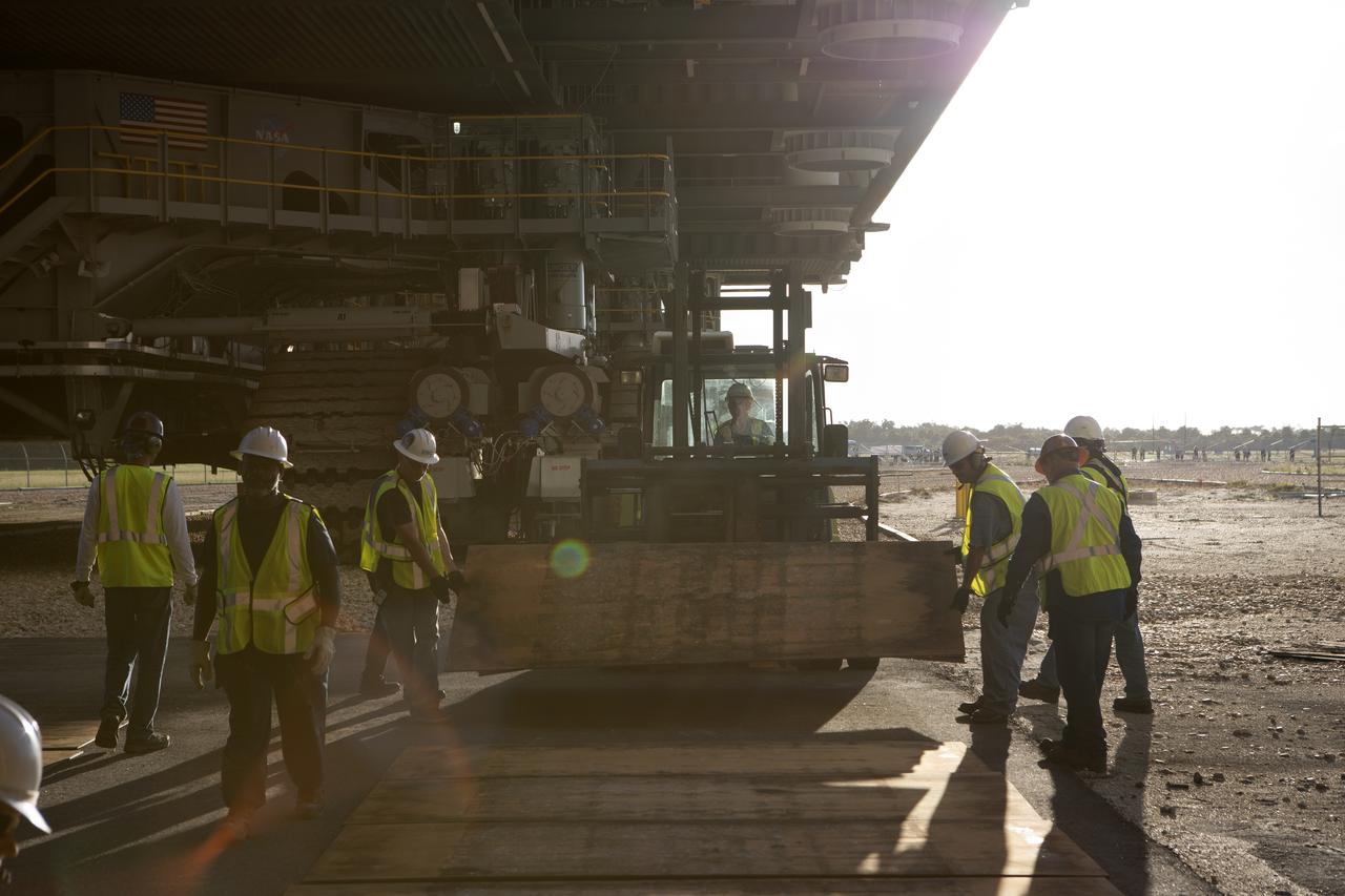 Technicians lay wooden planks down in the tracks to the entrance to High Bay 3 in the Vehicle Assembly Building (VAB), as mobile launcher, atop crawler-transporter 2, moves into the VAB on Sept. 8, 2018, at NASA's Kennedy Space Center in Florida. The mobile launcher departed Launch Pad 39B after several days of testing with the pad. This is the first time that the modified mobile launcher made the trip to the pad and the VAB. The mobile launcher will spend seven months in the VAB undergoing testing. The 380-foot-tall structure is equipped with the crew access arm and several umbilicals that will provide power, environmental control, pneumatics, communication and electrical connections to the agency's Space Launch System and Orion spacecraft. Exploration Ground Systems is preparing the ground systems necessary to launch SLS and Orion on Exploration Mission-1, missions to the Moon and on to Mars.
