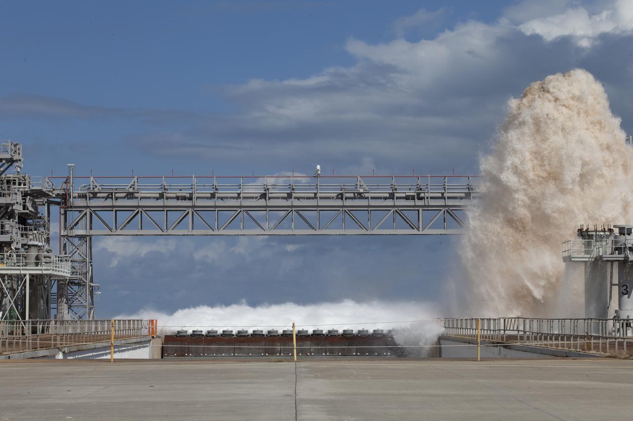 A flow test of the Ignition Overpressure Protection and Sound Suppression water deluge system is in progress at Launch Pad 39B at NASA's Kennedy Space Center in Florida, on Oct. 15, 2018. At peak flow, the water reaches about 100 feet in the air above the pad surface. It flows at high speed from a holding tank through new and modified piping and valves, the flame trench, flame deflector nozzles and mobile launcher interface risers. The testing is part of Exploration Ground System's preparation for the new Space Launch System rocket. Modifications were made to the pad after a previous wet flow test, increasing the performance of the system. During the launch of Exploration Mission-1 and subsequent missions, this water deluge system will release about 450,000 gallons of water across the mobile launcher and Flame Deflector to reduce the extreme heat and energy generated by the rocket during ignition and liftoff.