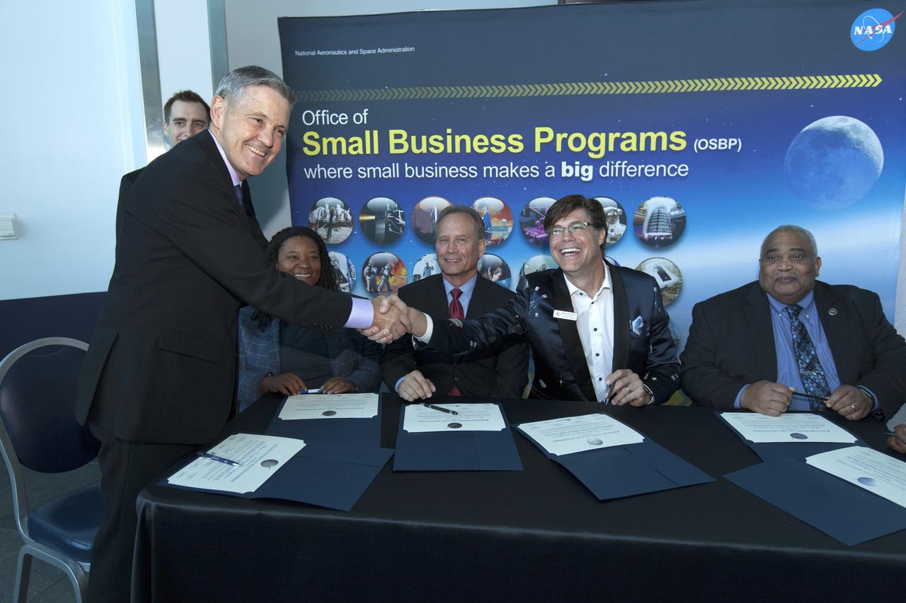 NASA Kennedy Space Center Director Bob Cabana, standing, shakes hands with Barry Hamilton, CEO and Founder of Red Canyon Software Inc., during the signing of a Mentor-Protégé Agreement on Oct. 23, 2018, at the NASA Business Opportunities Expo 2018 inside Cruise Terminal 6 at Port Canaveral in Florida. Seated, from left are Amber Allen, program analyst in the Launch Services Program; Steve Owens, deputy program manager with a.i. solutions Inc., a contractor at Kennedy; and Glenn Delgado, associate administrator, NASA Office of Small Business Programs. a.i. solutions will serve as the mentor to protégé Red Canyon Software. The 28th Business Opportunities Expo featured more than 200 businesses, large and small, and government exhibitors from throughout the Space Coast and the nation. The Business Opportunities Expo is facilitated by Kennedy's Small Business Programs Office and Prime Contractor Board, along with the U.S. Air Force 45th Space Wing and Canaveral Port Authority. Vendors from a variety of product and service areas, such as computer technology, engineering services, communication equipment and services, and construction and safety products, to name a few, were at the expo. Representatives from the 45th Space Wing, Kennedy prime contractors, NASA and many more agencies and organizations were on hand to provide information and answer questions.