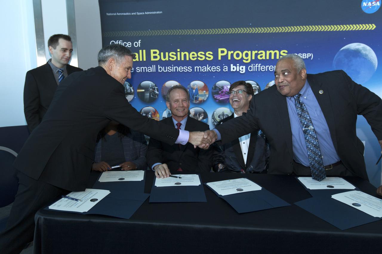 NASA Kennedy Space Center Director Bob Cabana, standing, shakes hands with Glenn Delgado, associate administrator, NASA Office of Small Business Programs, during the signing of a Mentor-Protégé Agreement on Oct. 23, 2018, at the NASA Business Opportunities Expo 2018 inside Cruise Terminal 6 at Port Canaveral in Florida. Seated, in view from left, are Steve Owens, deputy program manager with a.i. solutions Inc., a contractor at Kennedy; and Barry Hamilton, CEO and Founder of Red Canyon Software Inc. A.I. Solutions will serve as the mentor to protégé Red Canyon Software. The 28th Business Opportunities Expo featured more than 200 businesses, large and small, and government exhibitors from throughout the Space Coast and the nation. The Business Opportunities Expo is facilitated by Kennedy's Small Business Programs Office and Prime Contractor Board, along with the U.S. Air Force 45th Space Wing and Canaveral Port Authority. Vendors from a variety of product and service areas, such as computer technology, engineering services, communication equipment and services, and construction and safety products, to name a few, were at the expo. Representatives from the 45th Space Wing, Kennedy prime contractors, NASA and many more agencies and organizations were on hand to provide information and answer questions.