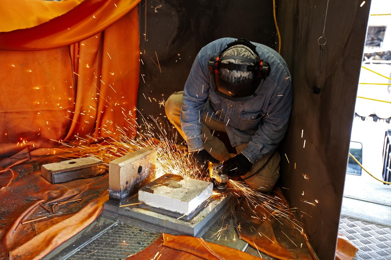 A Jacobs technician from the Launch Equipment Shop performs welding on the KAMAG spacecraft transporter on Oct. 26, 2018, inside a facility at the crawler yard at NASA’s Kennedy Space Center in Florida. The transporter is designed to carry heavy loads. Welding is being performed on the attach points that will hold the Orion transportation pallet in place. Testing of the pallet will be performed to support validation and verification of the attach fittings in the Multi-Payload Processing Facility.