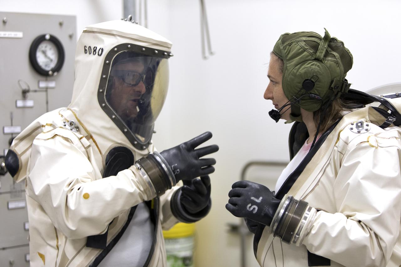 Technicans inside Kennedy's Multi-Payload Processing Facility do testing in SCAPE (Self-Contained Atmospheric Protective Ensemble) suits.
