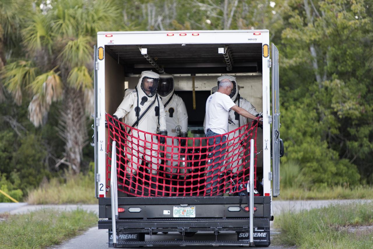 Operators wearing Self-Contained Atmospheric Protective Ensemble (SCAPE) suits are inside a transport vehicle near the Multi-Payload Processing Facility (MPPF) at NASA's Kennedy Space Center in Florida on Oct. 31, 2018. SCAPE operators, wearing the suits, will participate in a hypergolic systems hot flow test at the MPPF. The test will serve as operational validation of the hypergol subsystem and demonstrate that the hypergols subsystem can service the Orion spacecraft, flow fuel at the required rates, drain and de-service the system, and meet the intended timeline. SCAPE suite are used in operations involving toxic propellants and are supplied with air either through a hardline or through a self-contained environmental control unit.