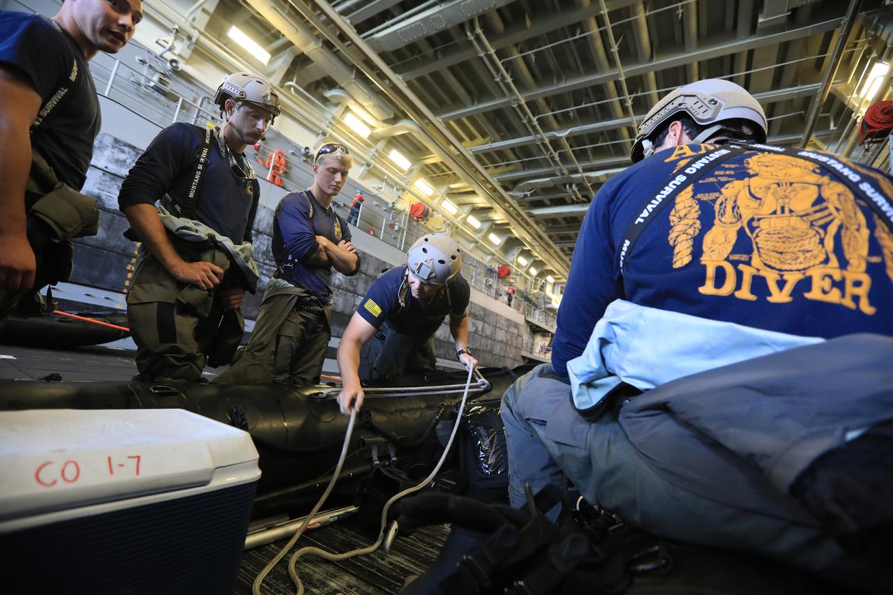 U.S. Navy divers from EOD Mobile Unit 11, MDS Company 11-7 prepare their small boat for launch in the well deck of the USS John P. Murtha, during Underway Recovery Test-7 (URT-7) on Oct. 31, 2018. The Exploration Ground Systems recovery team and the U.S. Navy are using a test version of the Orion crew module, several rigid hull inflatable boats and support equipment to verify and validate processes, procedures, hardware and personnel during recovery of Orion in open waters. The test is one in a series of tests to verify and validate procedures and hardware that will be used to recover the Orion spacecraft after it splashes down in the Pacific Ocean following deep space exploration missions. Orion will have emergency abort capability, sustain the crew during space travel and provide safe re-entry from deep space return velocities.
