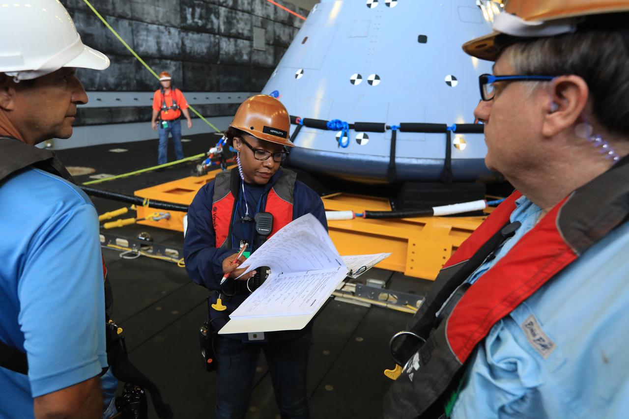 Tracy Parks, center, with Jacobs, serves as the Recovery Operations Integrator during Underway Recovery Test-7 (URT-7) aboard the USS John B. Murtha in the Pacific Ocean. On Oct. 31, 2018, during the second morning of URT-7, she reviews recovery operations with team members in the well deck of the ship. The Exploration Ground Systems recovery team and the U.S. Navy are using a test version of the Orion crew module, several rigid hull inflatable boats and support equipment to verify and validate processes, procedures, hardware and personnel during recovery of Orion in open waters. The test is one in a series of tests to verify and validate procedures and hardware that will be used to recover the Orion spacecraft after it splashes down in the Pacific Ocean following deep space exploration missions. Orion will have emergency abort capability, sustain the crew during space travel and provide safe re-entry from deep space return velocities.