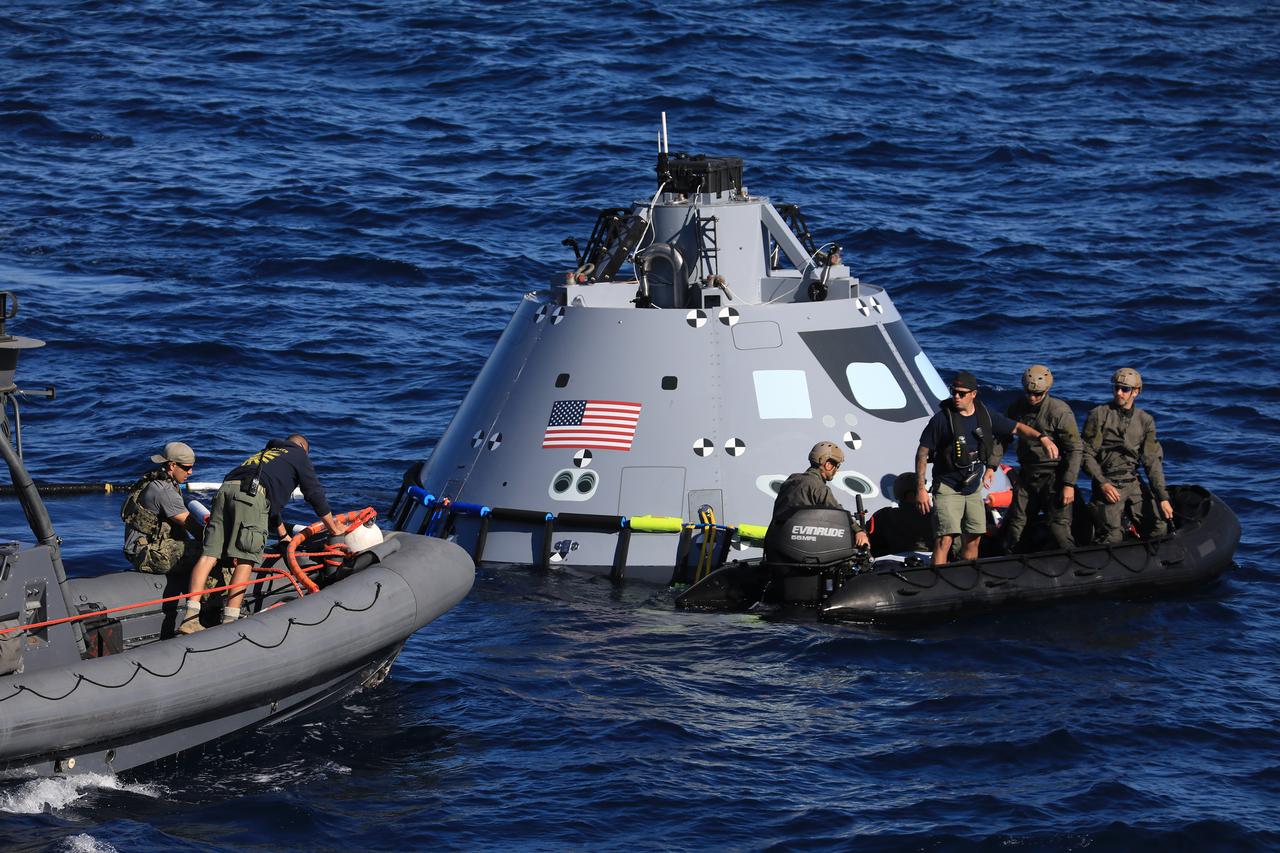 During Underway Recovery Test-7 (URT-7), U.S. Navy divers approach a test version of the Orion capsule to practice securing it for recovery into the well deck of an amphibious assault ship on Oct. 31, 2018 in the Pacific Ocean. The Exploration Ground Systems recovery team and the U.S. Navy work together to verify and validate procedures and hardware that will be used to recover the Orion spacecraft after it splashed down in the Pacific Ocean following deep space exploration missions. Orion will have emergency abort capability, sustain the crew during space travel and provide safe re-entry from deep space return velocities.