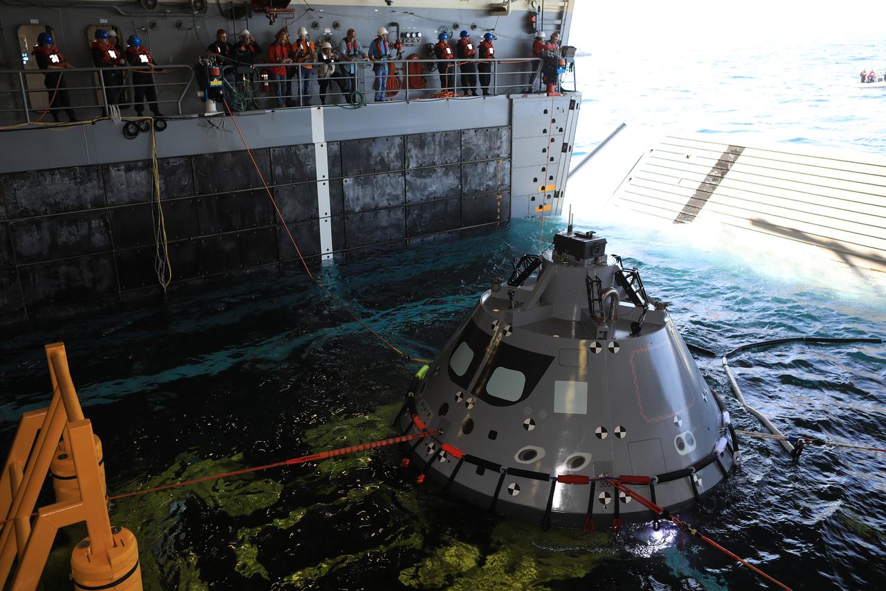 The Exploration Ground Systems Recovery Team, based out of Kennedy Space Center in Florida, practices bringing a test version of the Orion capsule inside the flooded well deck of the USS John P. Murtha and set it in a cradle as part of Underway Recovery Test-7 (URT-7) on Oct. 31, 2018, in the Pacific Ocean. URT-7 is one in a series of tests to verify and validate procedures and hardware that will be used to recover the Orion spacecraft after it splashes down in the Pacific Ocean following deep space exploration missions. Orion will have emergency abort capability, sustain the crew during space travel and provide safe re-entry from deep space return velocities.