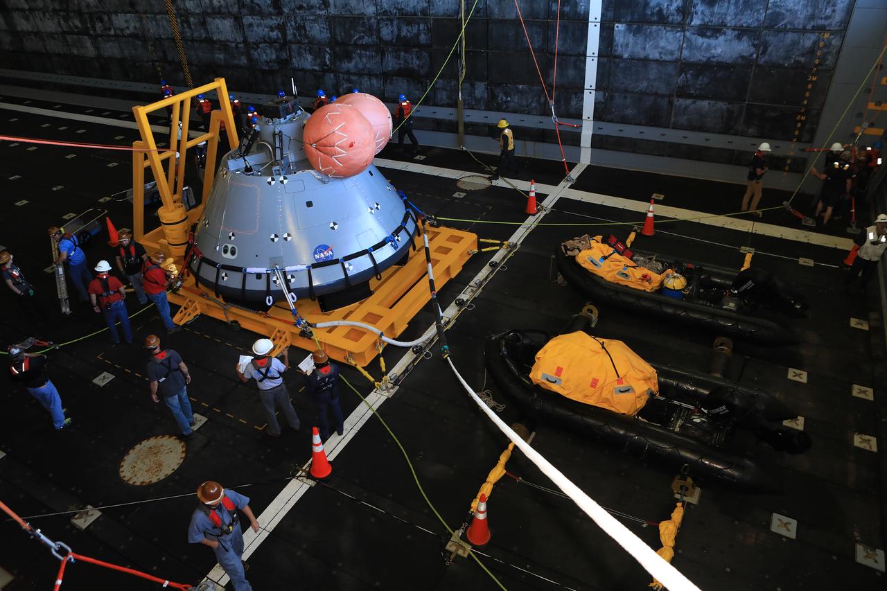 The Exploration Ground Systems (EGS) Recovery Team checks out the test version of the Orion capsule before releasing it into the open water of the Pacific Ocean during Underway Recovery Test-7 (URT-7) on Nov. 1, 2018, on the USS John P. Murtha. There are two large, orange mockup uprighting bags in this view, but when Orion actually splashes down there will be five. The test is one in a series of tests to verify and validate procedures and hardware that will be used to recover the Orion spacecraft after it splashes down in the Pacific Ocean following deep space exploration missions. Orion will have emergency abort capability, sustain the crew during space travel and provide safe re-entry from deep space return velocities.