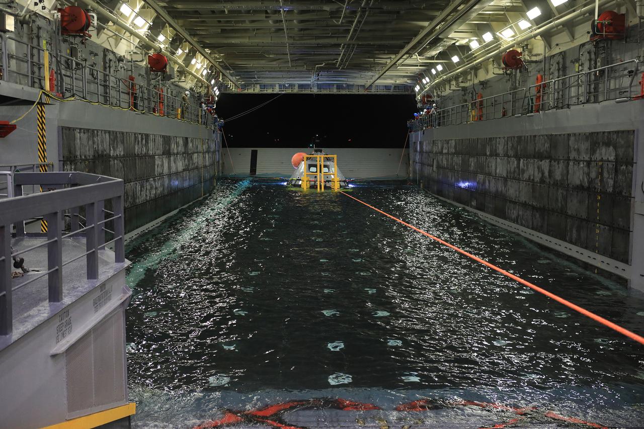 Inside the well deck of the USS John P. Murtha, a winch line pulls the test version of the Orion capsule onto its cradle while tending lines on the well walls help guide it into place during Underway Recovery Test-7 (URT-7) on Nov. 1, 2018. URT-7 is one in a series conducted the EGS Recovery Team to verify and validate procedures and hardware that will be used to recover the Orion spacecraft after it splashes down in the Pacific Ocean following deep space exploration missions. Orion will have emergency abort capability, sustain the crew during space travel and provide safe re-entry from deep space return velocities.