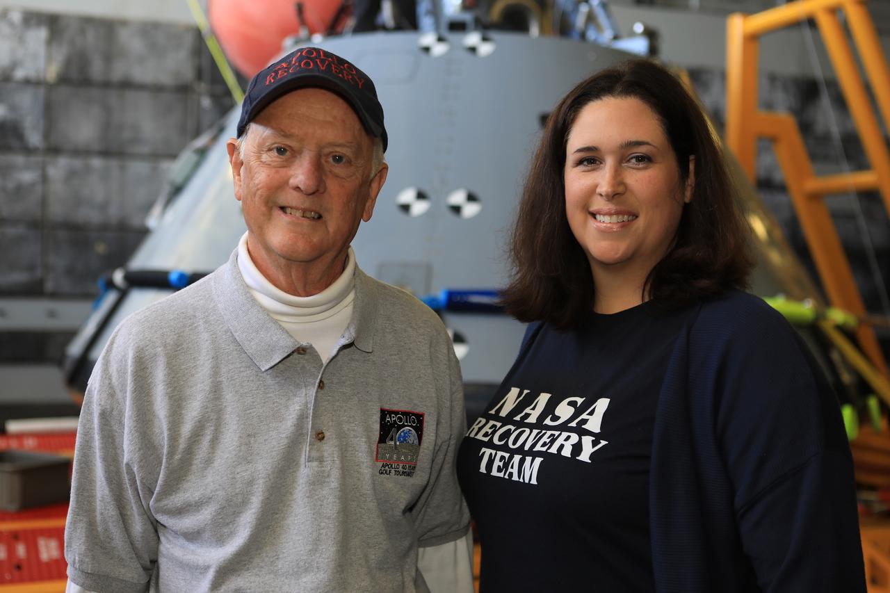 Apollo-era recovery engineer Milt Heflin, left, and NASA's Landing and Recovery Director Melissa Jones take time out from Underway Recovery Test-7 (URT-7) to pose in front of a test version of the Orion capsule in the well deck of the USS John P. Murtha on Nov. 3, 2018. The capsule is being used during testing. URT-7 is one in a series conducted by the Exploration Ground Systems Recovery Team to verify and validate procedures and hardware that will be used to recover the Orion spacecraft after it splashes down in the Pacific Ocean following deep space exploration missions. Orion will have emergency abort capability, sustain the crew during space travel and provide safe re-entry from deep space return velocities.