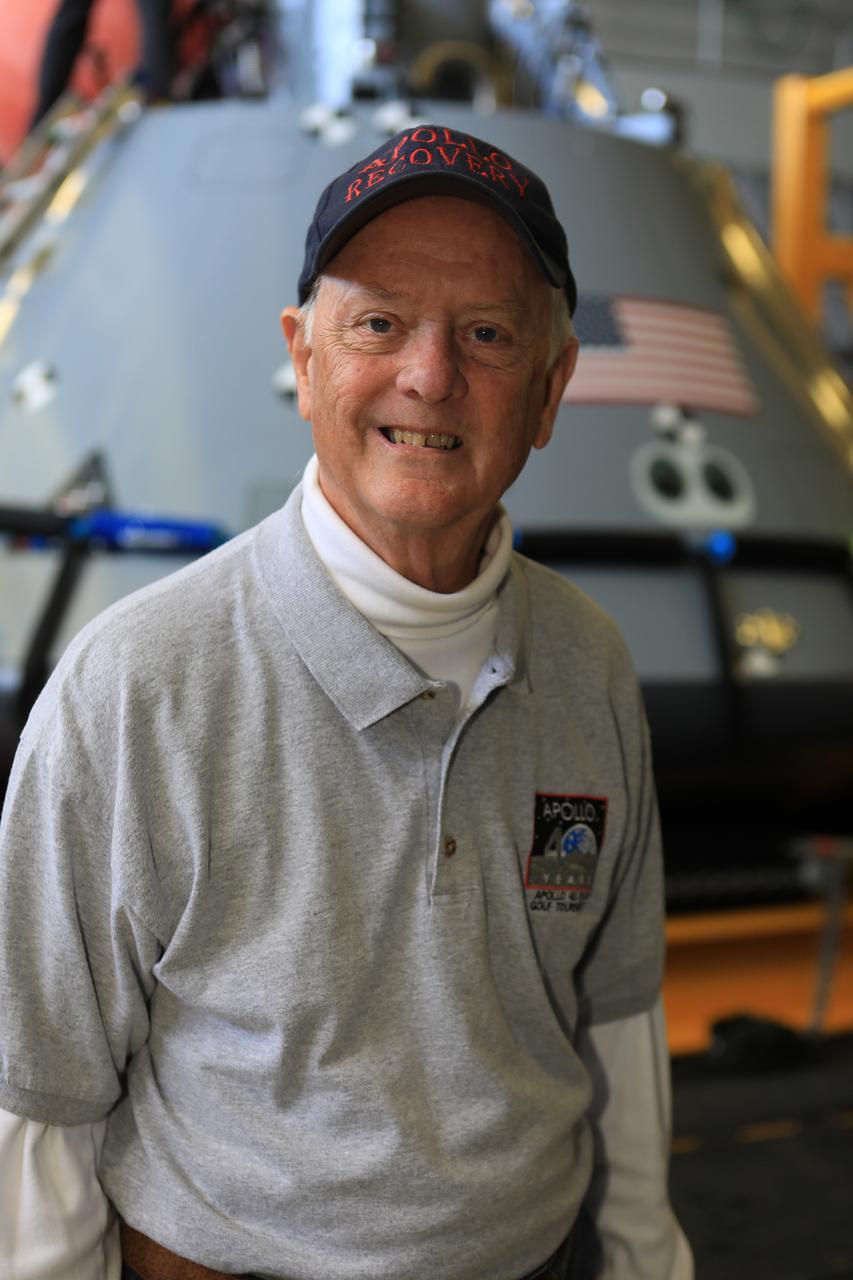 Apollo-era recovery engineer Milt Heflin takes time out from Underway Recovery Test-7 (URT-7) to pose in front of a test version of the Orion capsule in the well deck of the USS John P. Murtha on Nov. 3, 2018. The capsule is being used during testing. URT-7 is one in a series conducted by the Exploration Ground Systems Recovery Team to verify and validate procedures and hardware that will be used to recover the Orion spacecraft after it splashes down in the Pacific Ocean following deep space exploration missions. Orion will have emergency abort capability, sustain the crew during space travel and provide safe re-entry from deep space return velocities.