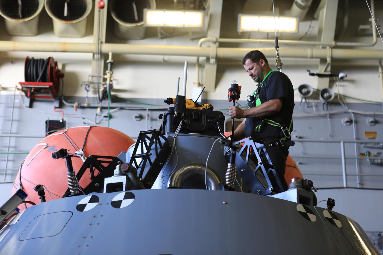 Open Water Recovery Lead Tim Goddard attaches lights to the top of the test version of the Orion capsule used during Underway Recovery Test-7 (URT-7) in the well deck of the USS John P. Murtha on Nov. 3, 2018. Goddard is the hardware expert in the open water and assists dive teams in the Pacific Ocean as they practice recovering the capsule during day and nighttime conditions. URT-7 is one in a series conducted by the Exploration Ground Systems Recovery Team to verify and validate procedures and hardware that will be used to recover the Orion spacecraft after it splashes down in the Pacific Ocean following deep space exploration missions. Orion will have emergency abort capability, sustain the crew during space travel and provide safe re-entry from deep space return velocities.
