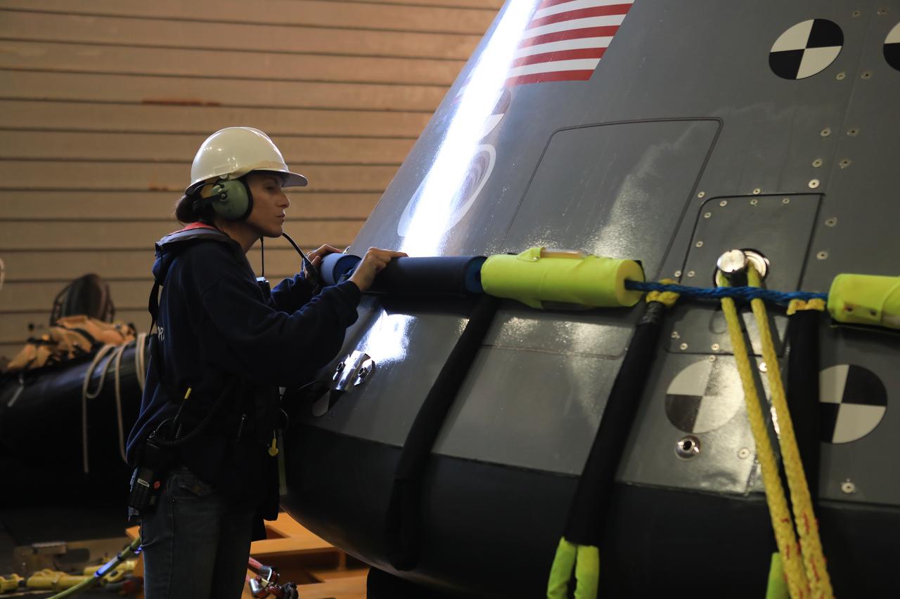 Lead NASA Operations Engineer Courtney Stern, with the Exploration Ground Systems (EGS) Recovery Team, inspects the pony collar on a test version of the Orion capsule in the well deck of the USS John P. Murtha before a night deployment on Nov. 3, 2018, during Underway Recovery Test-7 (URT-7). URT-7 is one in a series conducted by the EGS Recovery Team to verify and validate procedures and hardware that will be used to recover the Orion spacecraft after it splashes down in the Pacific Ocean following deep space exploration missions. Orion will have emergency abort capability, sustain the crew during space travel and provide safe re-entry from deep space return velocities.
