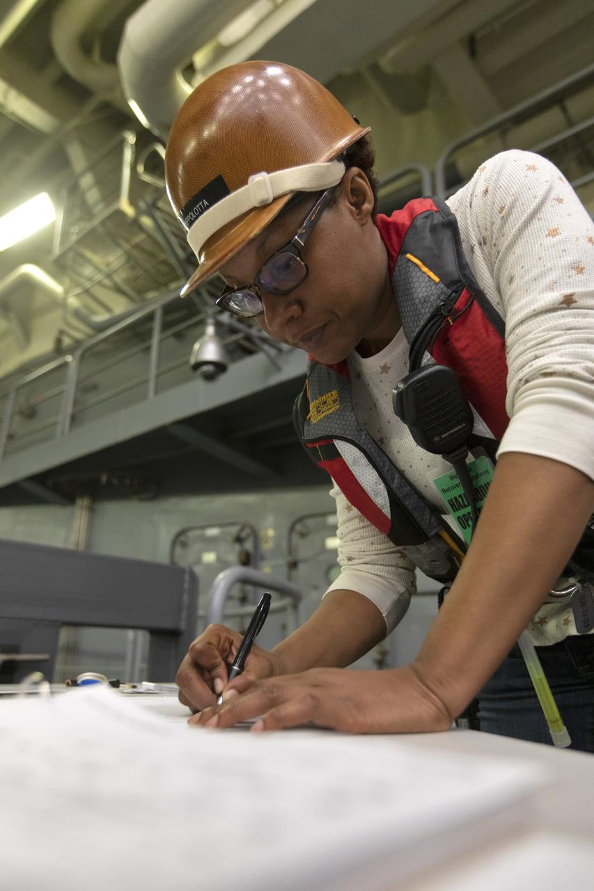 Tracy Parks, Recovery Operations integrator with Jacobs, reviews procedures during Underway Recovery Test-7 (URT-7), aboard the USS John P. Murtha on Nov. 4, 2018. NASA's Recovery Team, along with the U.S. Navy, practice recovering a test version of the Orion capsule as part of URT-7 in the Pacific Ocean. URT-7 is one in a series of tests to verify and validate procedures and hardware that will be used to recover the Orion spacecraft after it splashes down in the Pacific Ocean following deep space exploration missions. Orion will have emergency abort capability, sustain the crew during space travel and provide safe re-entry from deep space return velocities.