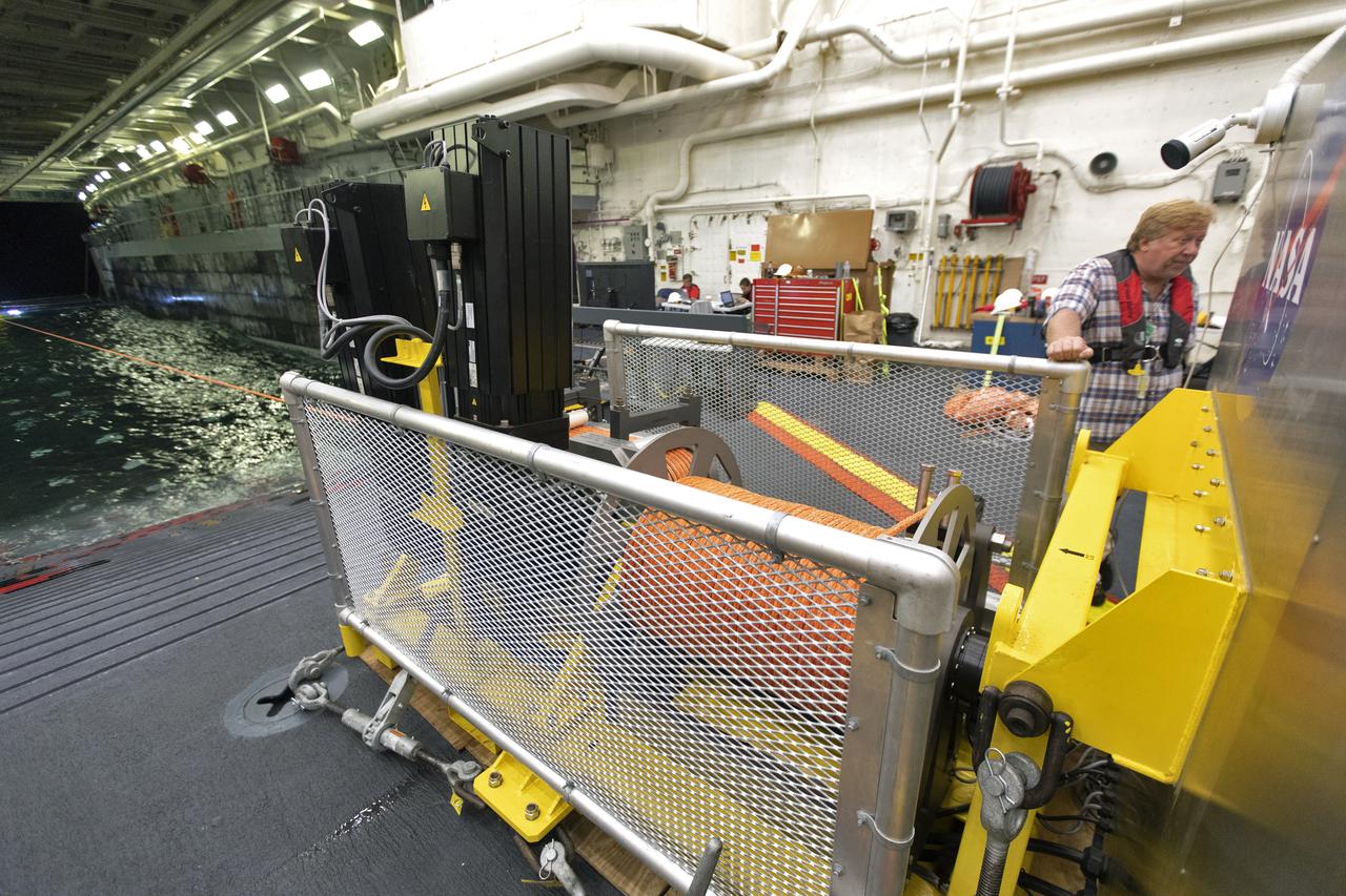 Inside the well deck of the USS John P. Murtha, a winch line is being used to tow a test version of the Orion crew module into the well deck during Underway Recovery Test-7 (URT-7), during the evening on Nov. 4, 2018. NASA's Recovery Team, along with the U.S. Navy, are practicing recovery of the Orion capsule as part of URT-7 in the Pacific Ocean. URT-7 is one in a series of tests to verify and validate procedures and hardware that will be used to recover the Orion spacecraft after it splashes down in the Pacific Ocean following deep space exploration missions. Orion will have emergency abort capability, sustain the crew during space travel and provide safe re-entry from deep space return velocities.