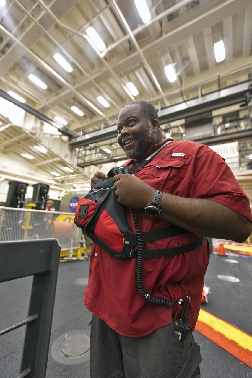 Johnny Bryant, communications officer, speaks with team members in the well deck of the USS John P. Murtha, during Underway Recovery Test-7 (URT-7) on Nov. 4, 2018. NASA's Recovery Team, along with the U.S. Navy, are practicing recovery of a test version of the Orion in the Pacific Ocean. URT-7 is one in a series of tests to verify and validate procedures and hardware that will be used to recover the Orion spacecraft after it splashes down in the Pacific Ocean following deep space exploration missions. Orion will have emergency abort capability, sustain the crew during space travel and provide safe re-entry from deep space return velocities.
