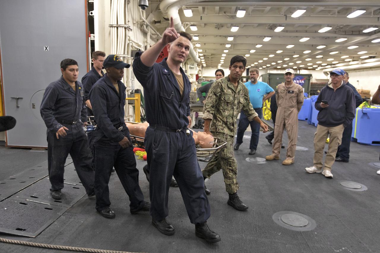 U.S. Navy recovery team members practice bringing an astronaut aboard the USS John P. Murtha, using a dummy, during Underway Recovery Test-7 (URT-7) on Nov. 5, 2018. NASA astronaut Don Pettit, in tan coveralls, looks on and discusses plans for moving the astronauts after returning from deep space. NASA's Recovery Team, along with the U.S. Navy, are practicing recovery of a test version of the Orion in the Pacific Ocean. URT-7 is one in a series of tests to verify and validate procedures and hardware that will be used to recover the Orion spacecraft after it splashes down in the Pacific Ocean following deep space exploration missions. Orion will have emergency abort capability, sustain the crew during space travel and provide safe re-entry from deep space return velocities.