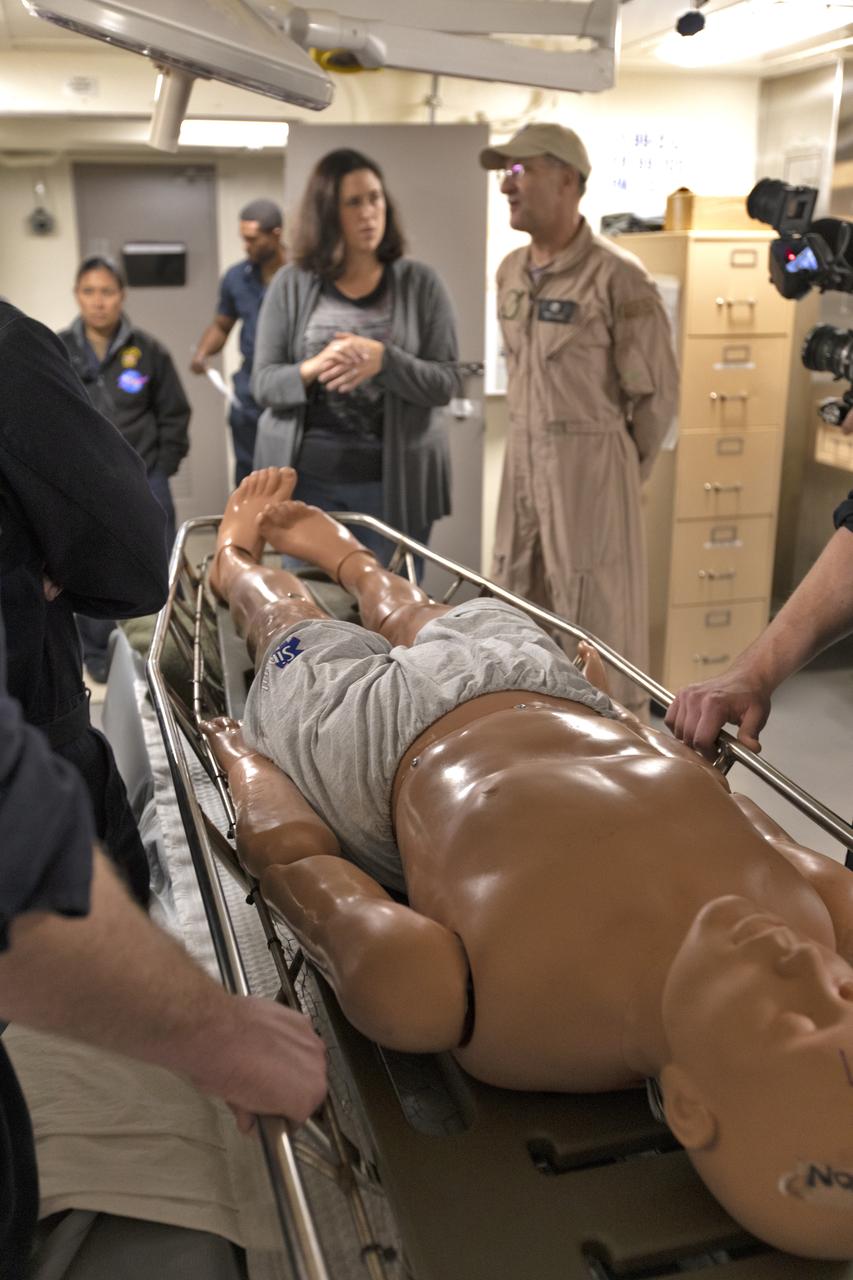 U.S. Navy recovery team members practice bringing an astronaut aboard the USS John P. Murtha, using a dummy, during Underway Recovery Test-7 (URT-7) on Nov. 5, 2018. NASA astronaut Don Pettit, in tan coveralls, looks on and discusses plans for moving the astronauts after returning from deep space. At left is Melissa Jones, NASA Landing and Recovery director. NASA's Recovery Team, along with the U.S. Navy, are practicing recovery of a test version of the Orion in the Pacific Ocean. URT-7 is one in a series of tests to verify and validate procedures and hardware that will be used to recover the Orion spacecraft after it splashes down in the Pacific Ocean following deep space exploration missions. Orion will have emergency abort capability, sustain the crew during space travel and provide safe re-entry from deep space return velocities.