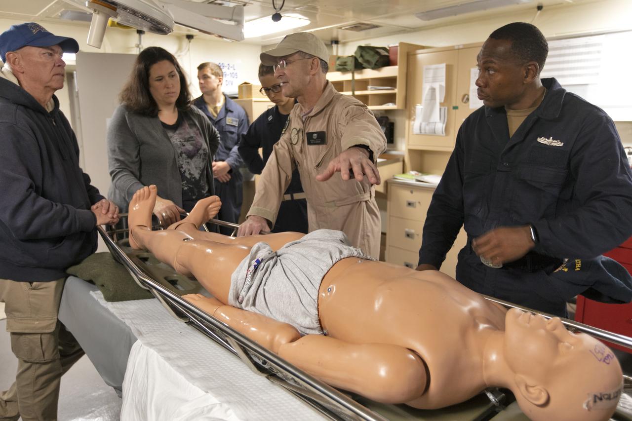 U.S. Navy recovery team members practice bringing an astronaut aboard the USS John P. Murtha, using a dummy, during Underway Recovery Test-7 (URT-7) on Nov. 5, 2018. NASA astronaut Don Pettit, in tan coveralls, looks on and discusses plans for moving the astronauts after returning from deep space. At left is Melissa Jones, NASA Landing and Recovery director. NASA's Recovery Team, along with the U.S. Navy, are practicing recovery of a test version of the Orion in the Pacific Ocean. URT-7 is one in a series of tests to verify and validate procedures and hardware that will be used to recover the Orion spacecraft after it splashes down in the Pacific Ocean following deep space exploration missions. Orion will have emergency abort capability, sustain the crew during space travel and provide safe re-entry from deep space return velocities.