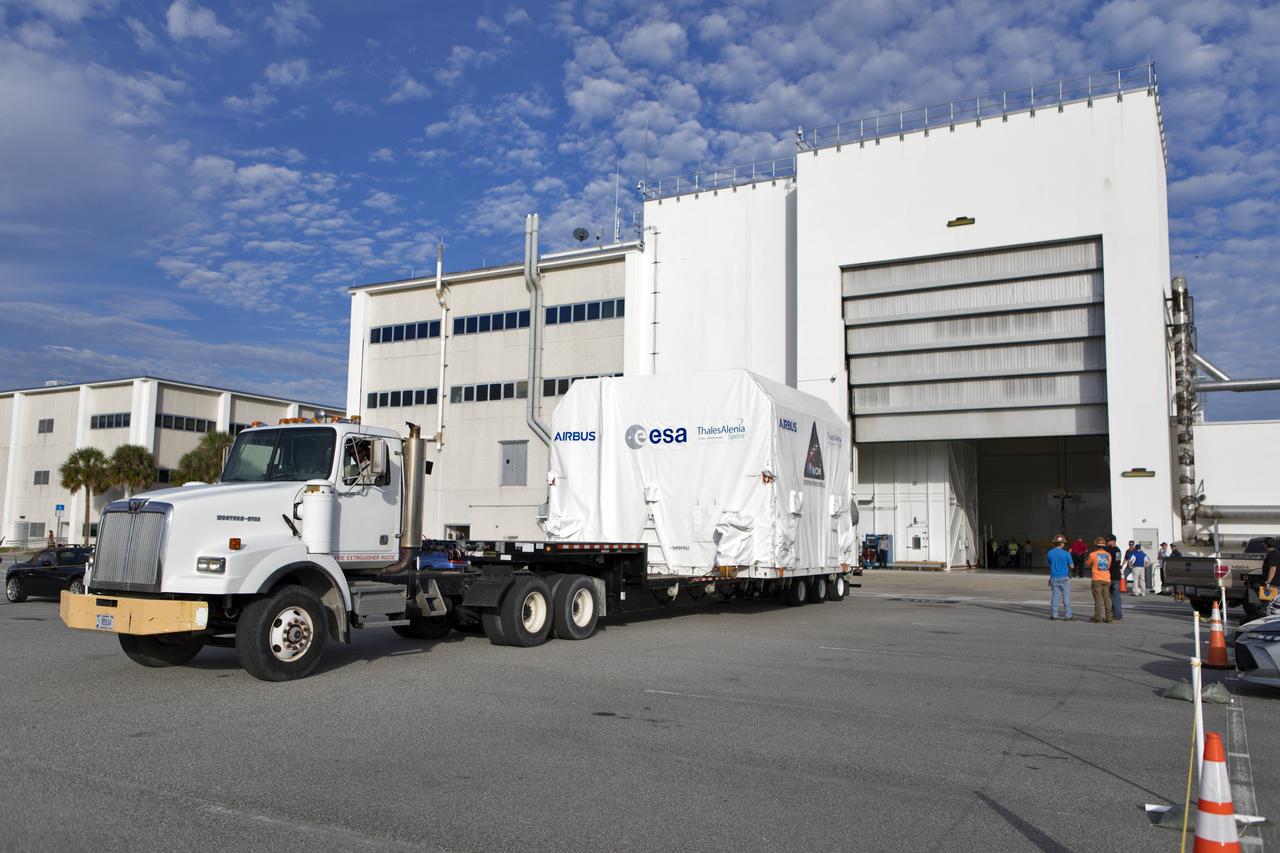 A flatbed truck carrying the European Space Agency's European Service Module (ESM) in its shipping container begins to back into the airlock of the Neil Armstrong Operations and Checkout Building on Nov. 6, 2018, at NASA's Kennedy Space Center in Florida. The ESM will supply the main propulsion system and power to the Orion spacecraft for Exploration Mission-1 (EM-1), a mission to the Moon. The ESM also will house air and water for astronauts on future missions. EM-1 will be an uncrewed flight test that will provide a foundation for human deep space exploration to destinations beyond Earth orbit. EM-1 will be the first integrated test of NASA's Space Launch System, Orion and the ground systems at Kennedy.