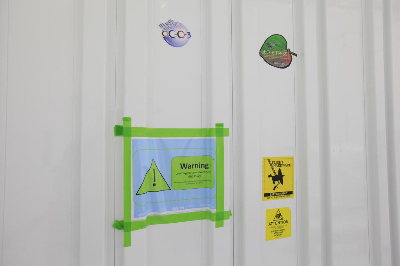 A transportation container carrying NASA’s Orbiting Carbon Observatory 3, or OCO-3, payload sits at the Space Station Processing Facility high bay at the agency’s Kennedy Space Center in Florida bearing a warning sign of low oxygen levels from an active GN2 (gaseous nitrogen that creates a dry atmosphere) purge prior to its move to the SpaceX facility on March 18, 2019. The OCO-3 payload will be stowed in the trunk of SpaceX’s Dragon spacecraft and will launch aboard a Falcon 9 rocket on the company’s 17th Commercial Resupply Services mission to the International Space Station. Launch is scheduled for April 25, 2019, from Launch Complex 40 at Cape Canaveral Air Force Station. Once the payload reaches the station, it will be removed from Dragon and robotically installed on the exterior of the orbiting laboratory’s Japanese Experiment Module Exposed Facility Unit, where it will measure and map carbon dioxide from space to provide further understanding of the relationship between carbon and climate. 