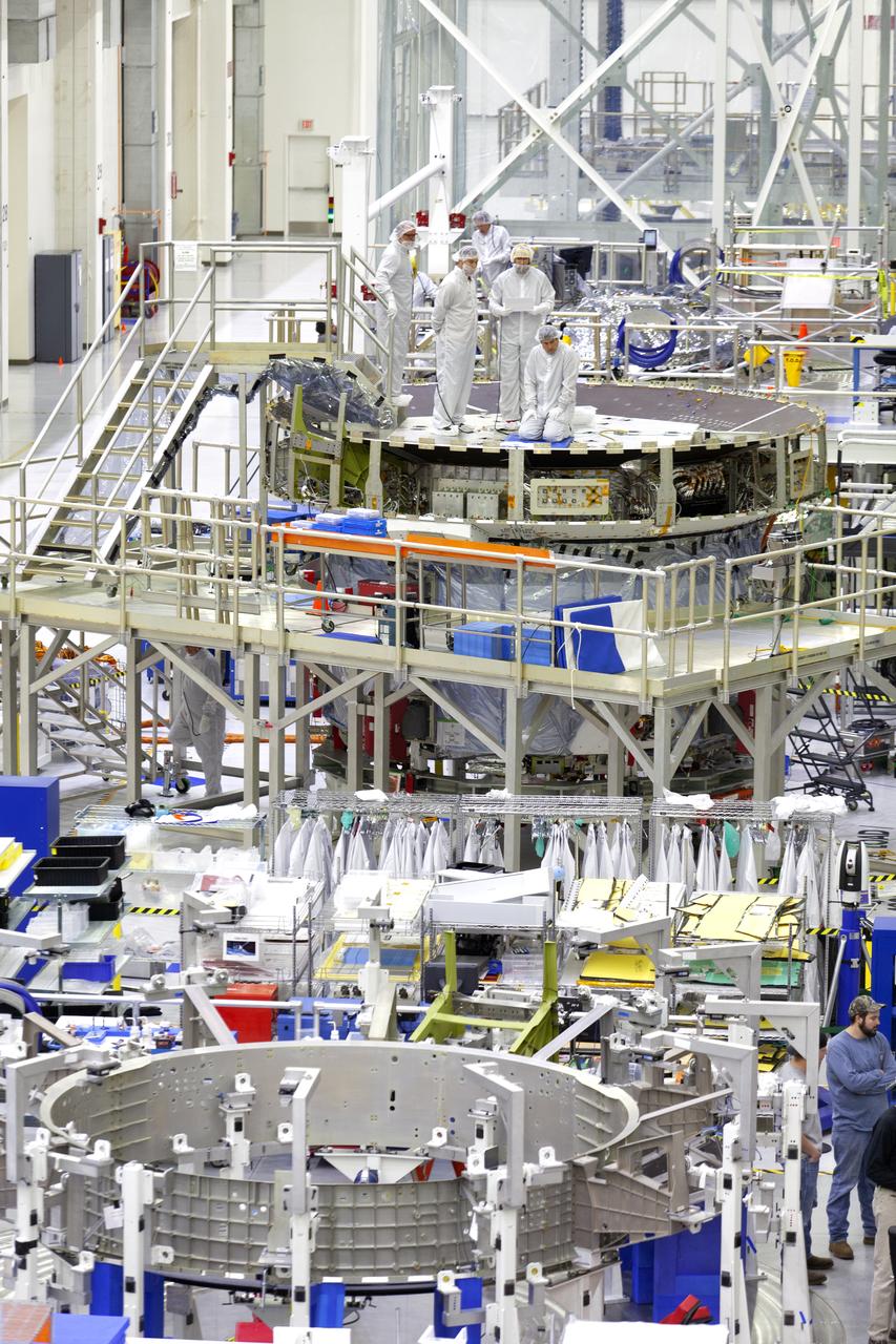 A view inside the Neil Armstrong Operations and Checkout Building high bay at NASA’s Kennedy Space Center in Florida on March 21, 2019. In the foreground is the Orion crew module adapter for Exploration Mission-2 (EM-2). In the back, European Space Agency and Airbus workers are on the work stand that contains the European Service Module that will serve as the powerhouse for Orion for Exploration Mission-1 (EM-1). For EM-1, Orion will launch atop the Space Launch System rocket from Launch Pad 39B. The spacecraft will travel thousands of miles past the Moon on an approximately three-week test flight. Orion will return to Earth and splashdown in the Pacific Ocean off the coast of California, where it will be retrieved and returned to Kennedy.