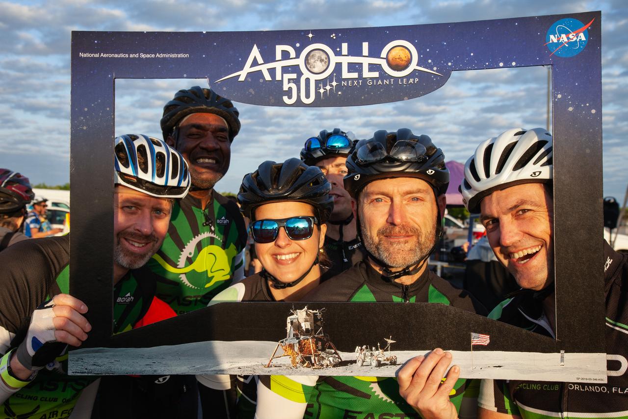 Cyclists pose for a photo within a frame promoting the 50th anniversary of the first Apollo Moon landing prior to the start of Kennedy Space Center’s annual Tour de KSC. The bicycle tour took place March 30, giving Kennedy employees and guests the opportunity to choose from three different routes that ranged from seven to 33 miles along some of the Florida spaceport’s most notable facilities such as the Vehicle Assembly Building, the Shuttle Landing Facility and historic Launch Pad 39A, among others. 